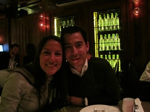 A photo of a man and a woman sitting at arestaurant table. In the background there are stacked some green bottles.