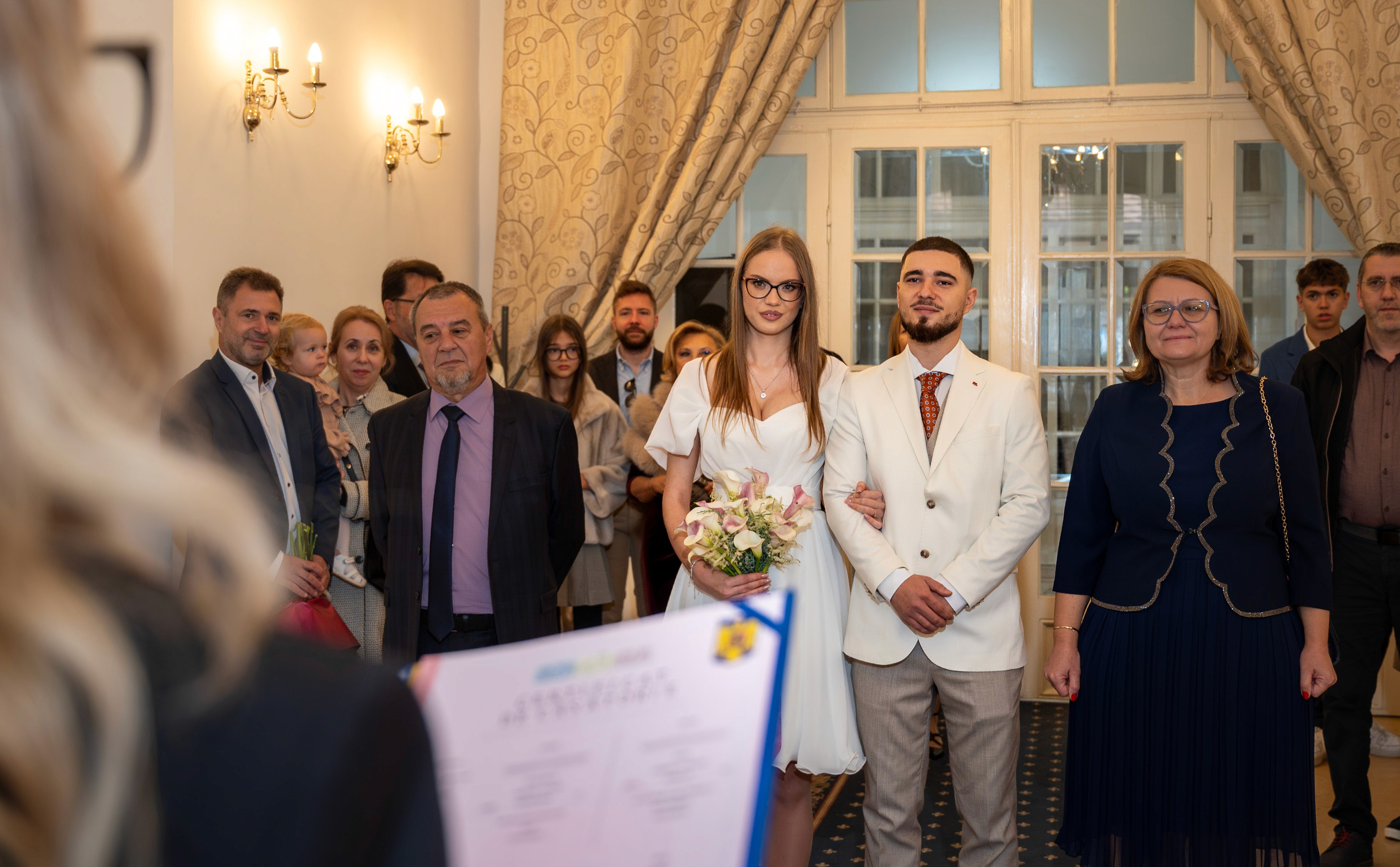Cuplu în timpul ceremoniei de cununie civilă, alături de familie și invitați.