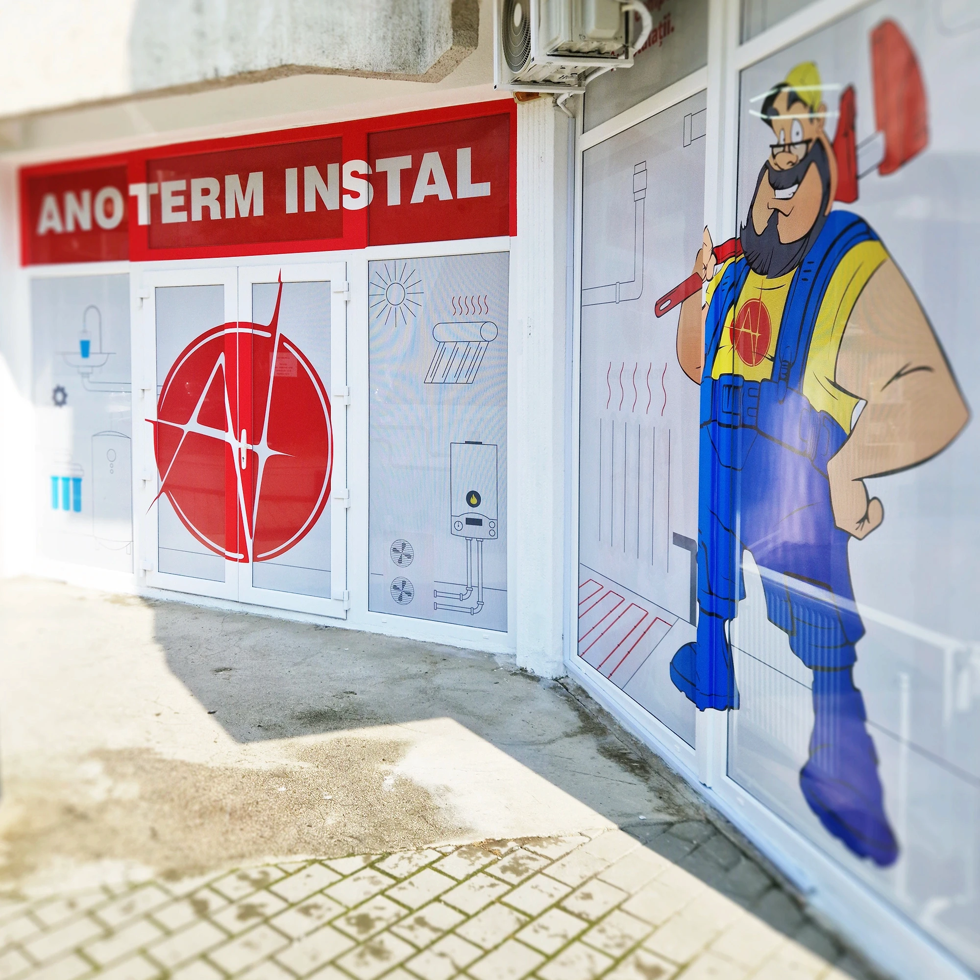Fațada magazinului Ano Term Instal după colantare, cu logo și mascotă pe geam, Iași
