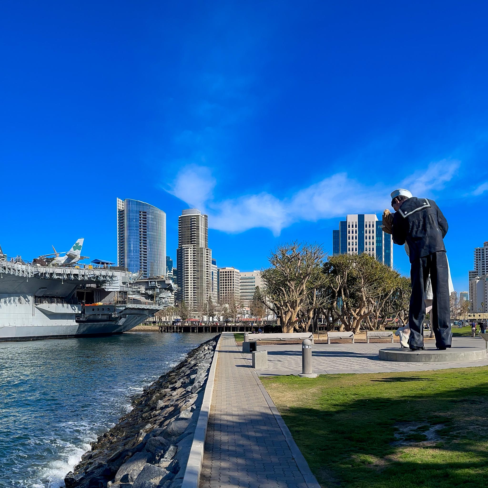 Cruise ship docked in front of statue of figures in an embrace 