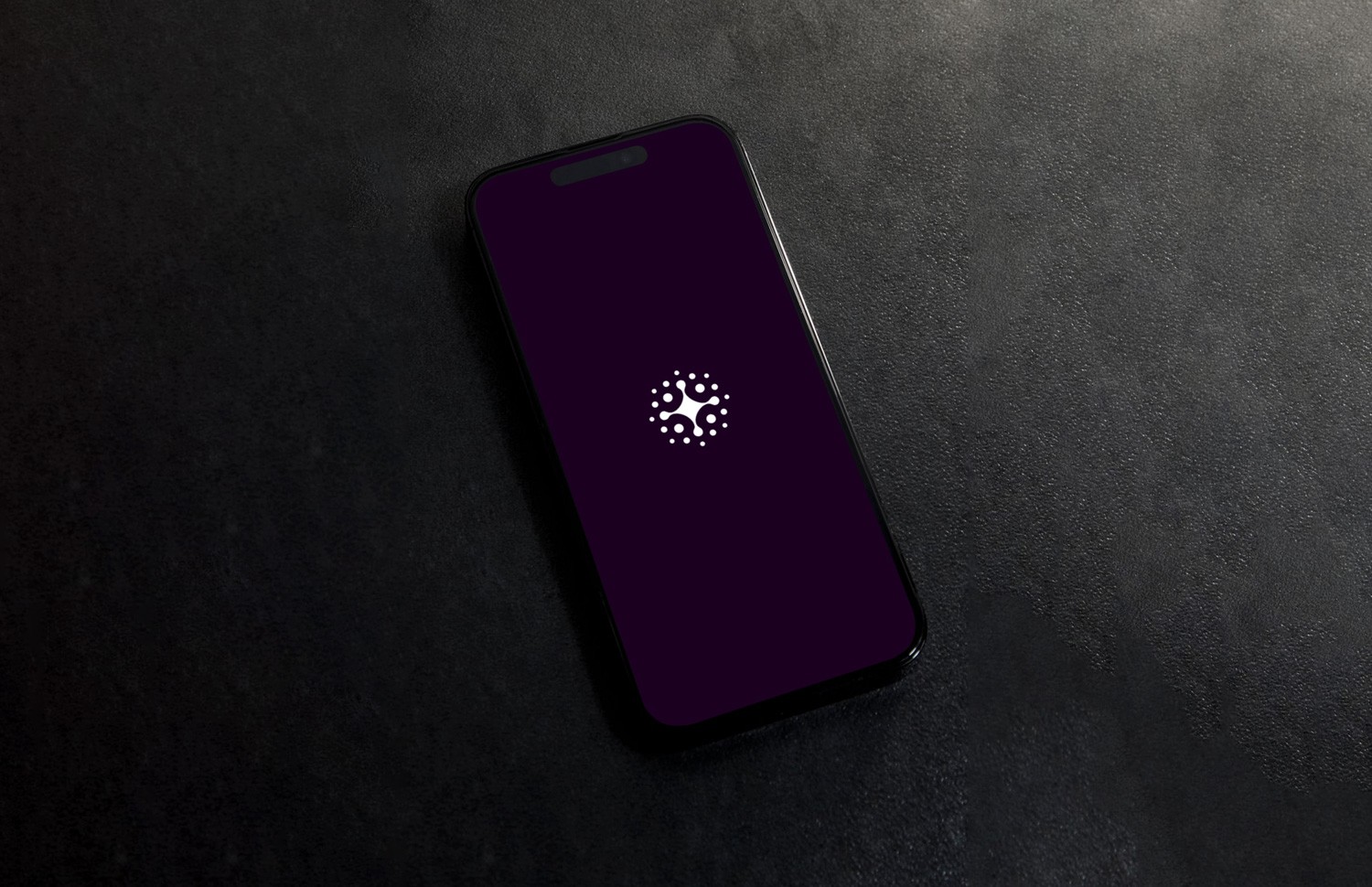 Smart speaker with glowing top on a table next to a soft light lamp, with a phone