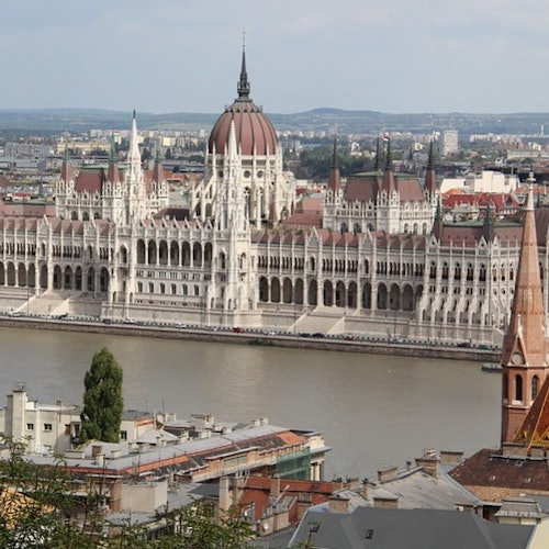 Vista del Parlamento Ungherese sul fiume Danubio con edifici cittadini in primo piano.