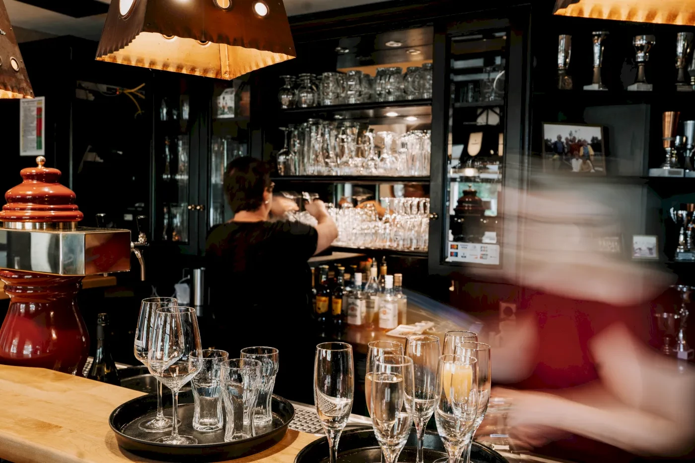 Ein Barkeeper hinter der Theke, die Gläser poliert. Gläser und Flaschen stehen bereit. Blick auf die Bar im Restaurant.