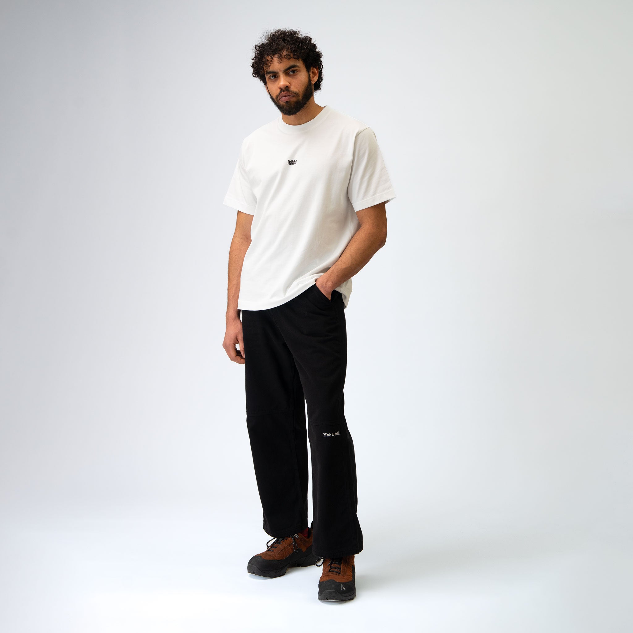 Man wearing a white t-shirt and black pants on a white background