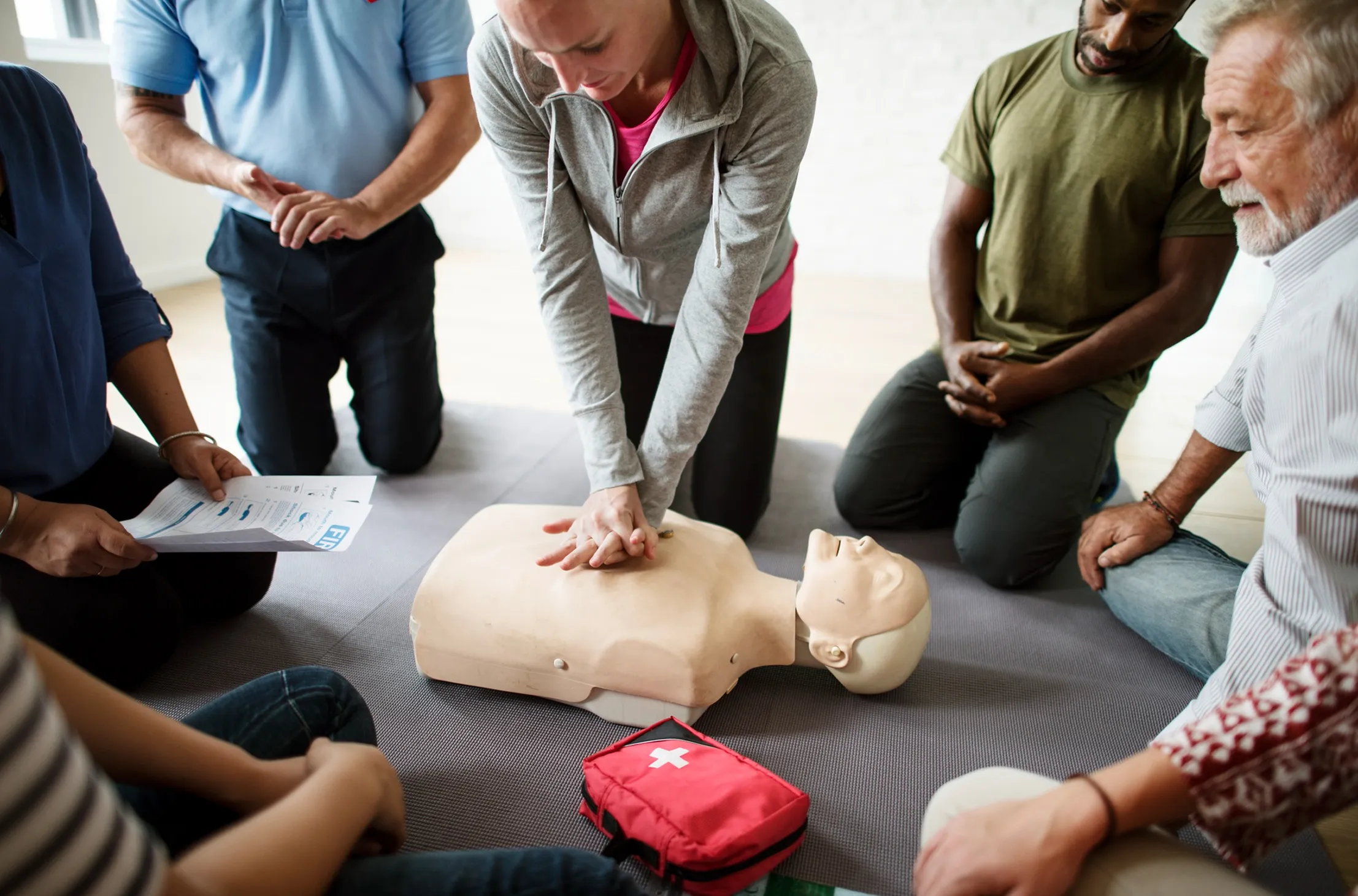 Stagiaire pratiquant un geste de secours sur mannequin, encadré par un formateur.