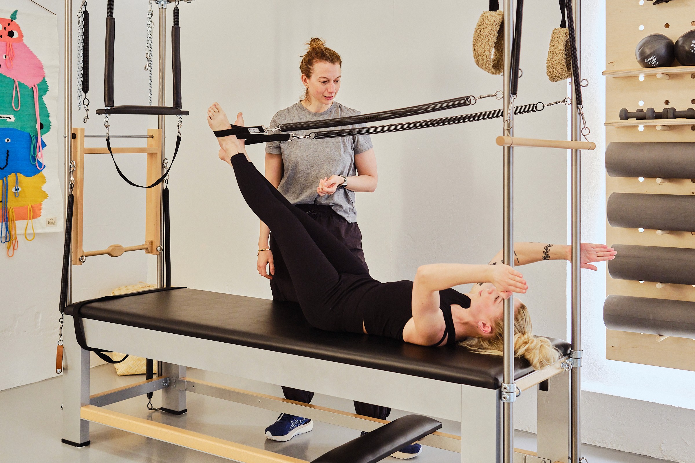 Kvinde bliver instrueret i pilates på cadillac maskinen