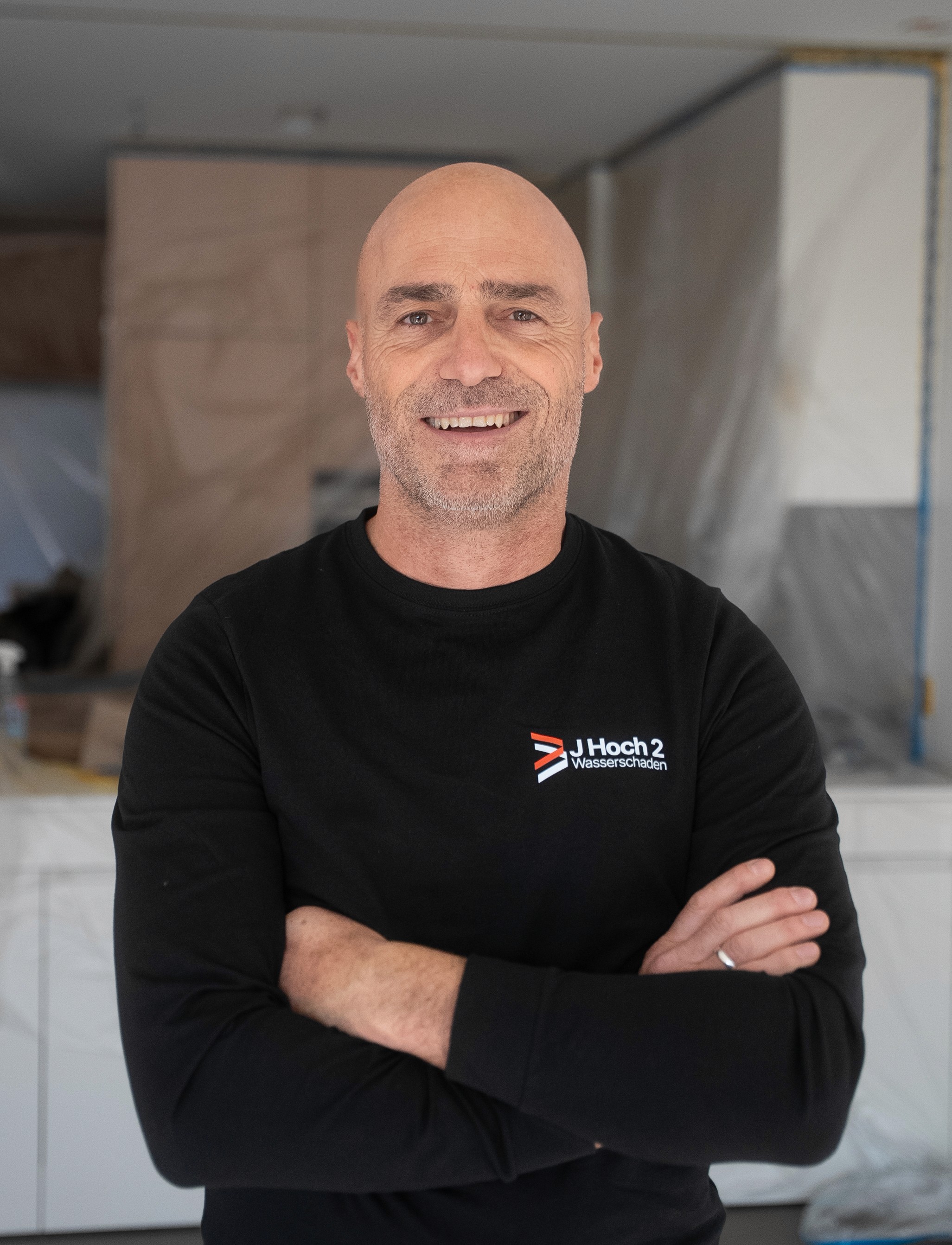 A woman with short curly hair wearing a black t-shirt looks into the camera.
