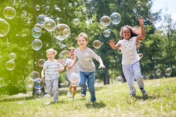 Kids running and playing with soap bubbles