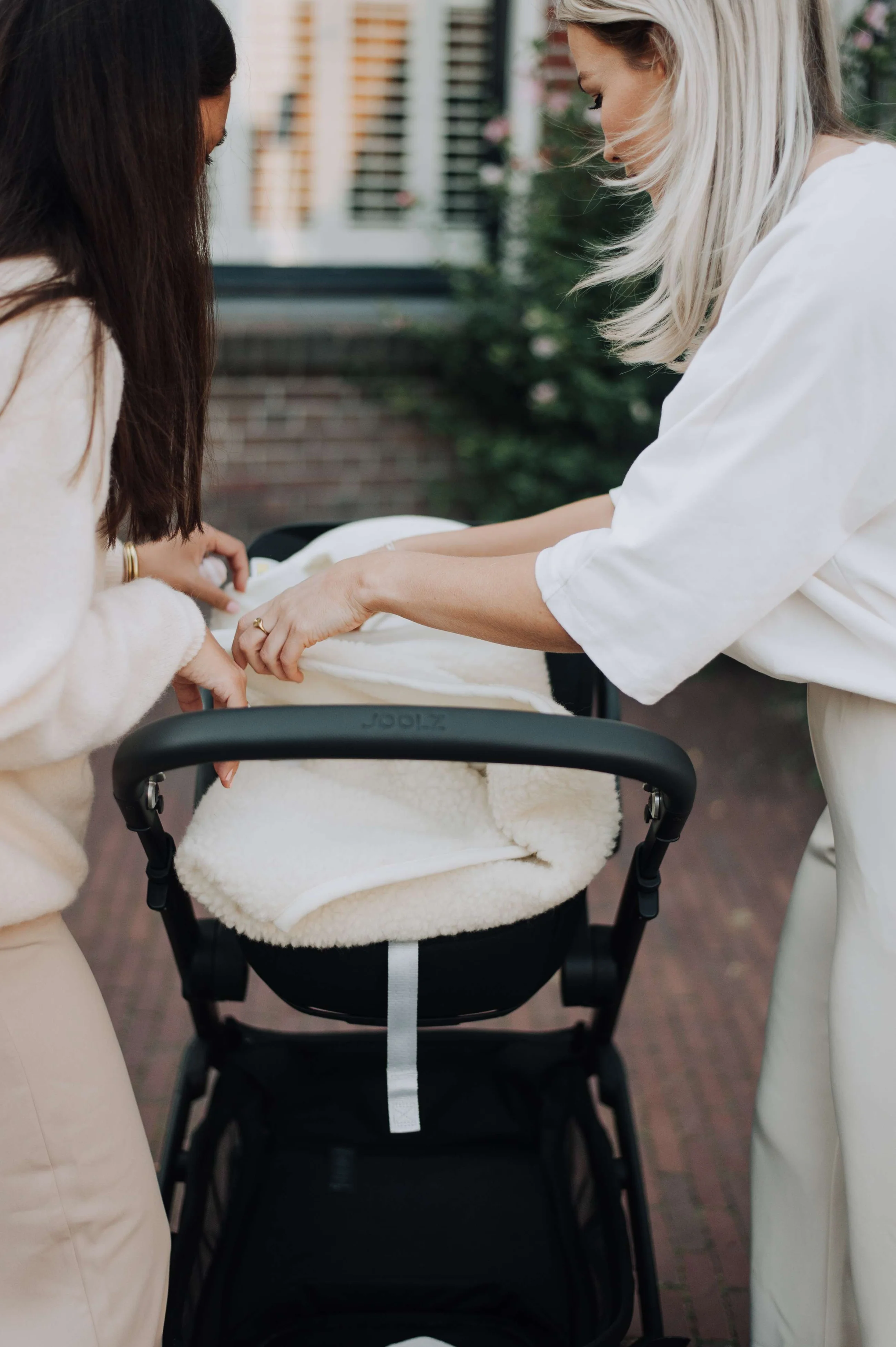 Twee moeders leggen samen een wollen deken klaar in de kinderwagen