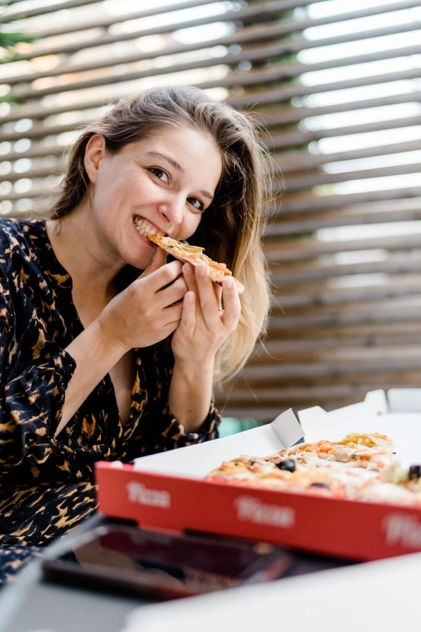 Boudoir-style photo of a woman enjoying pizza, capturing self-love and art.
