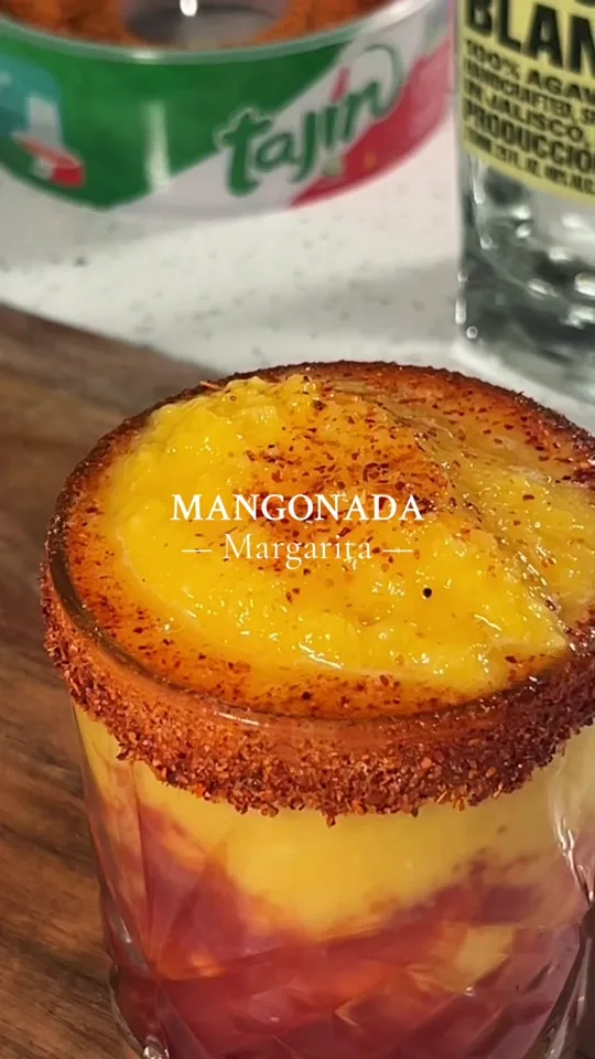 Close-up of a Mangonada Margarita cocktail with 'Tajin' label visible.