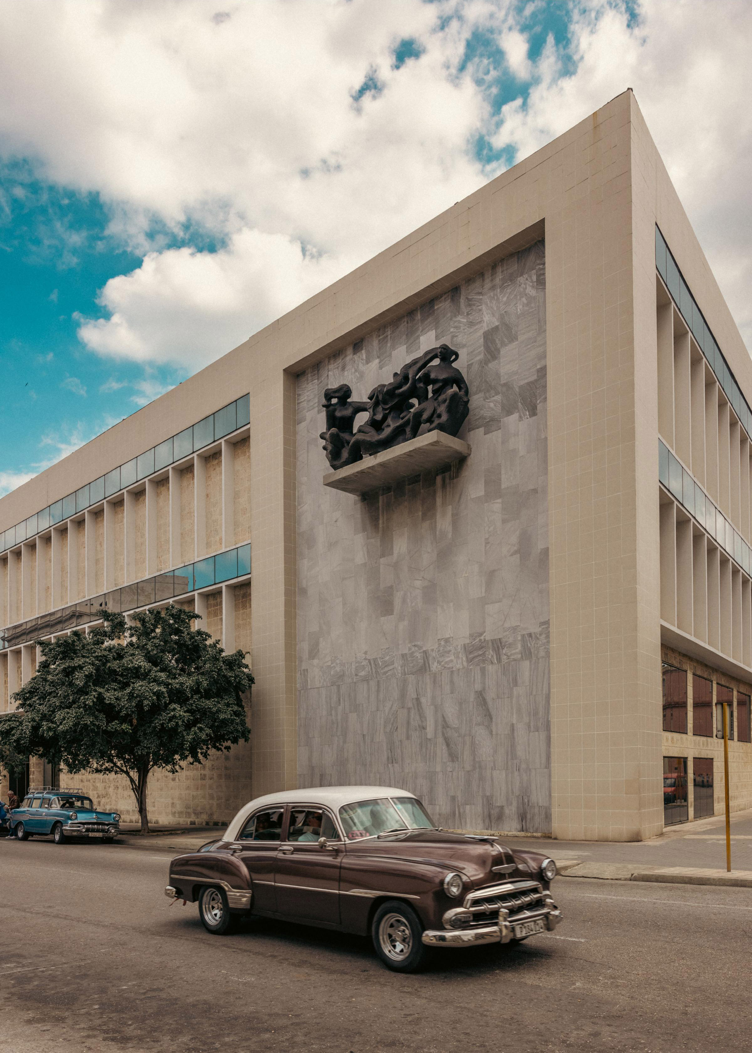 A 1952 Chevrolet Styleline Deluxe Sedan drives past the Arte Cubano building, one of two structures at The Museo Nacional de Bellas Artes that house the world’s most comprehensive collection of Cuban art.