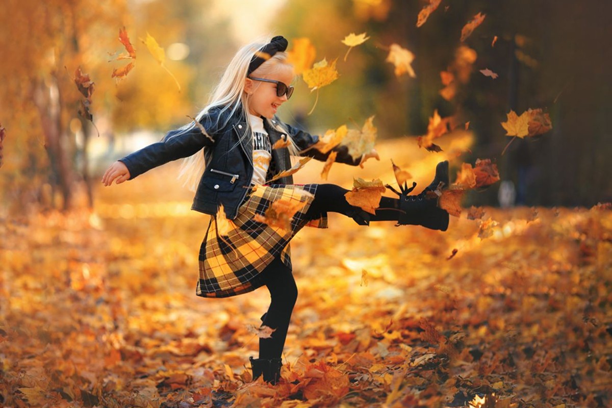 Girl playing with autumn leaves during a park photoshoot