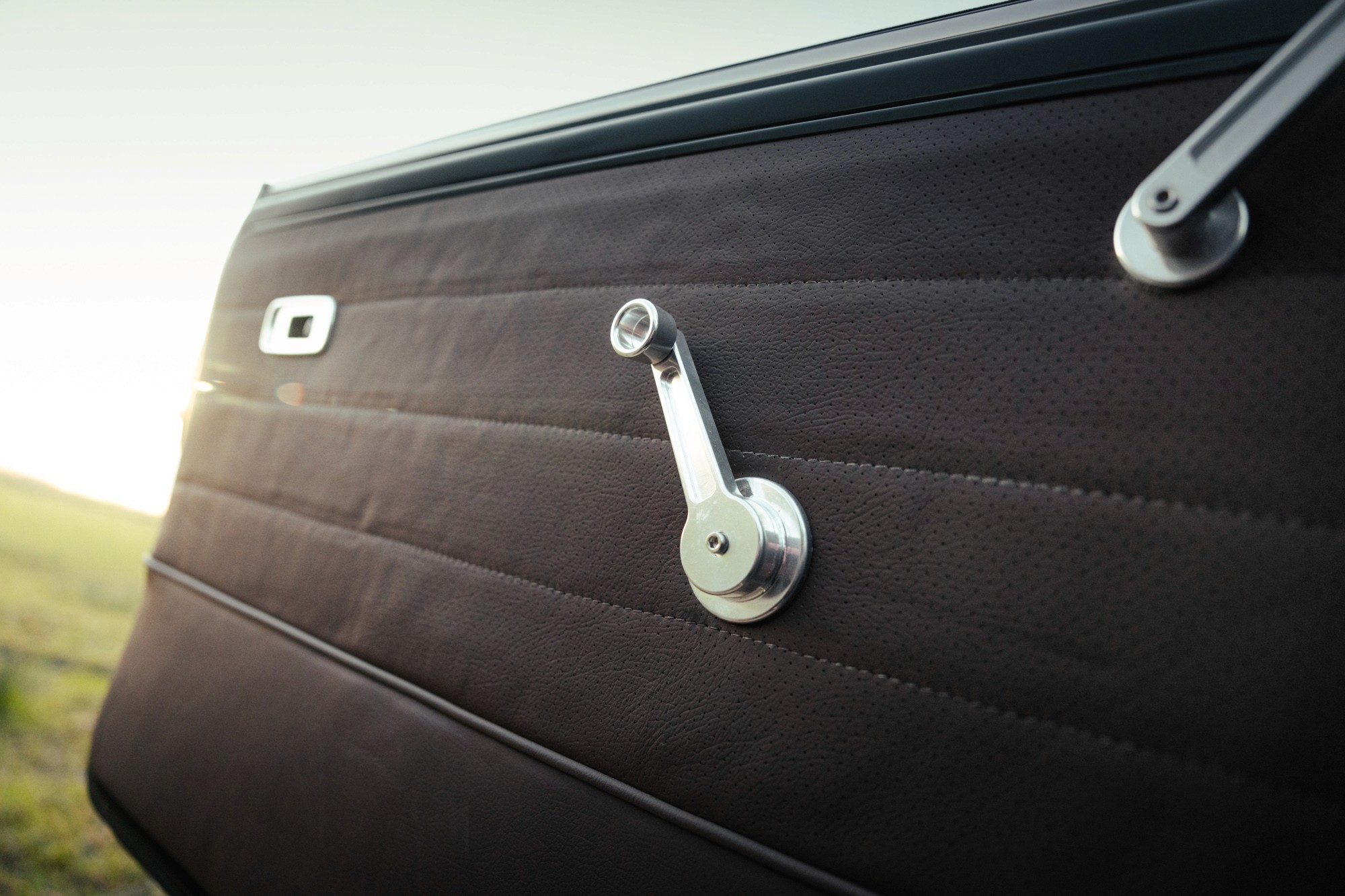 Detail of a mini classic door panel with a manual window crank made of full aluminium brooks motors