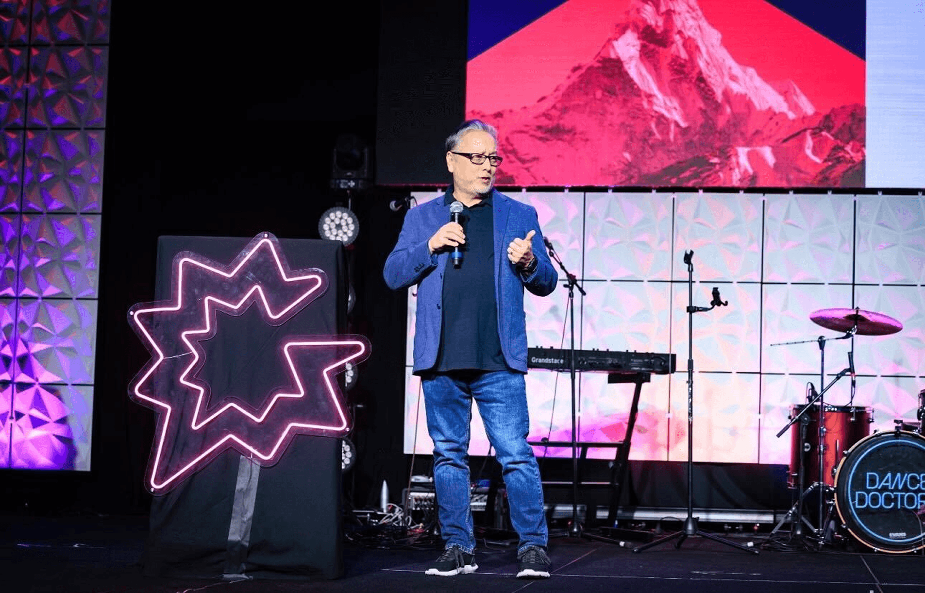 Rob Moyer presenting on stage with pink neon Gong logo backdrop