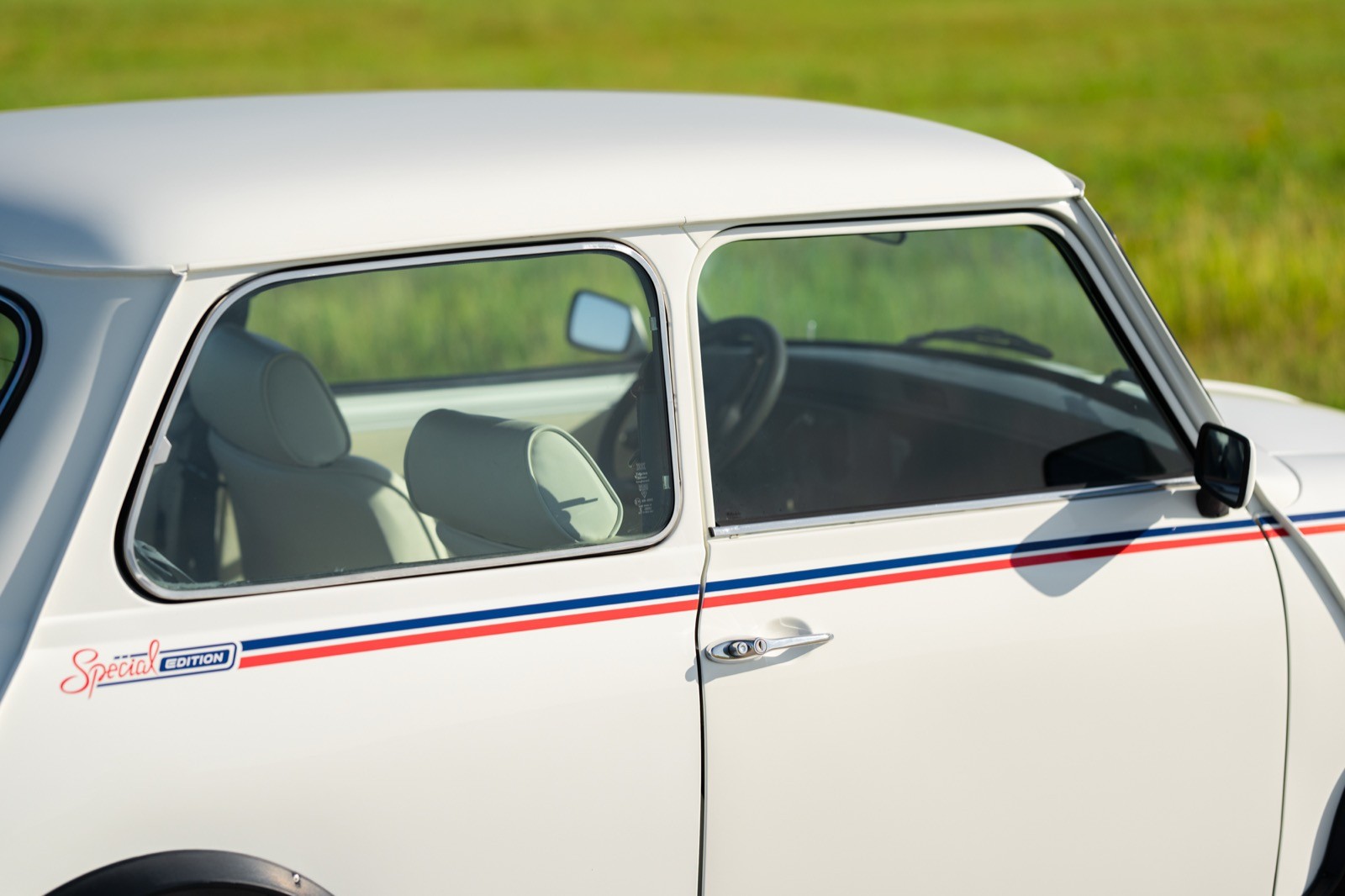 Close-up of a vintage car's side window, revealing a green interior with a backseat visible.