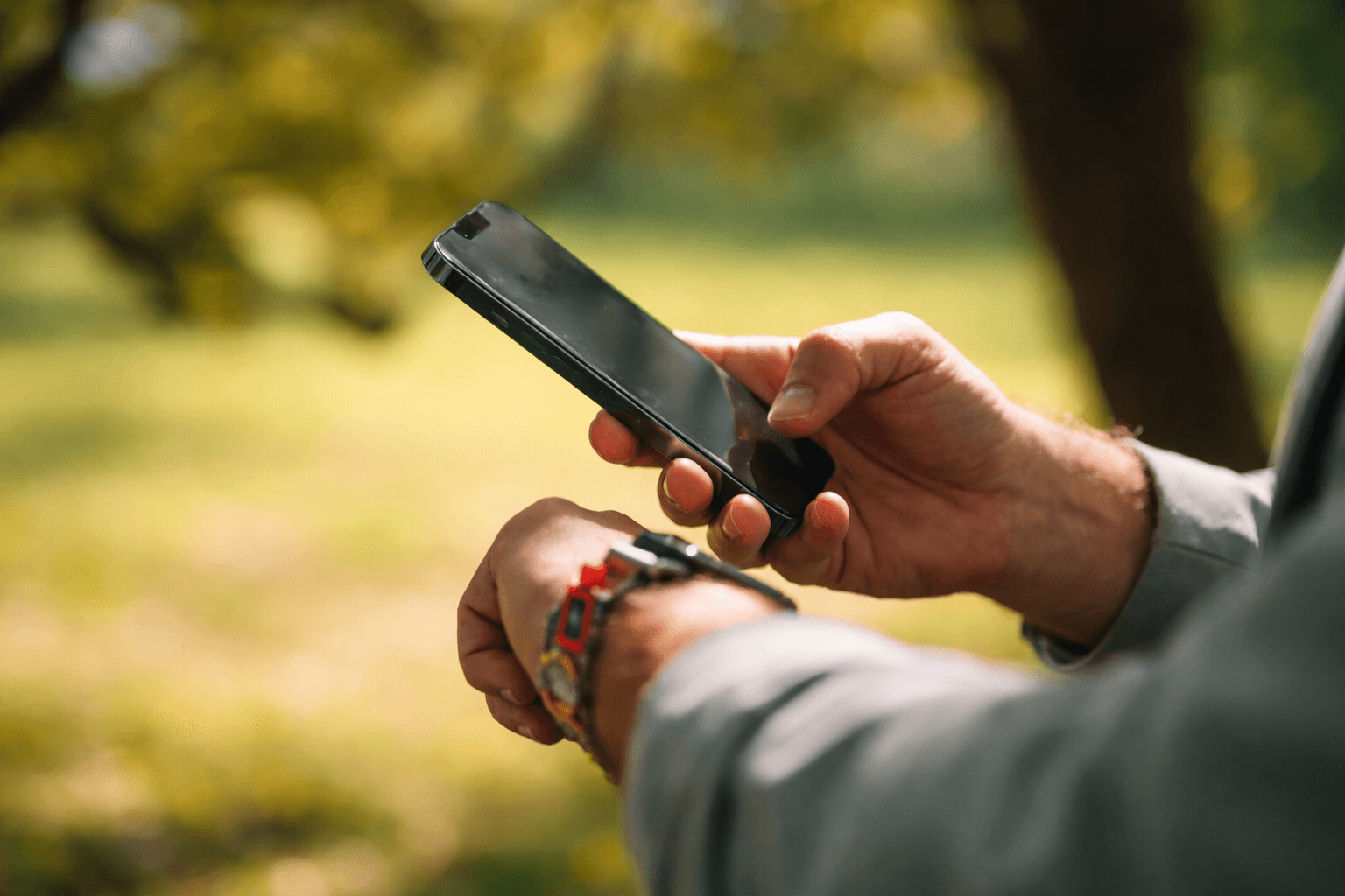 Person using a smartphone outdoors in warm sunlight.