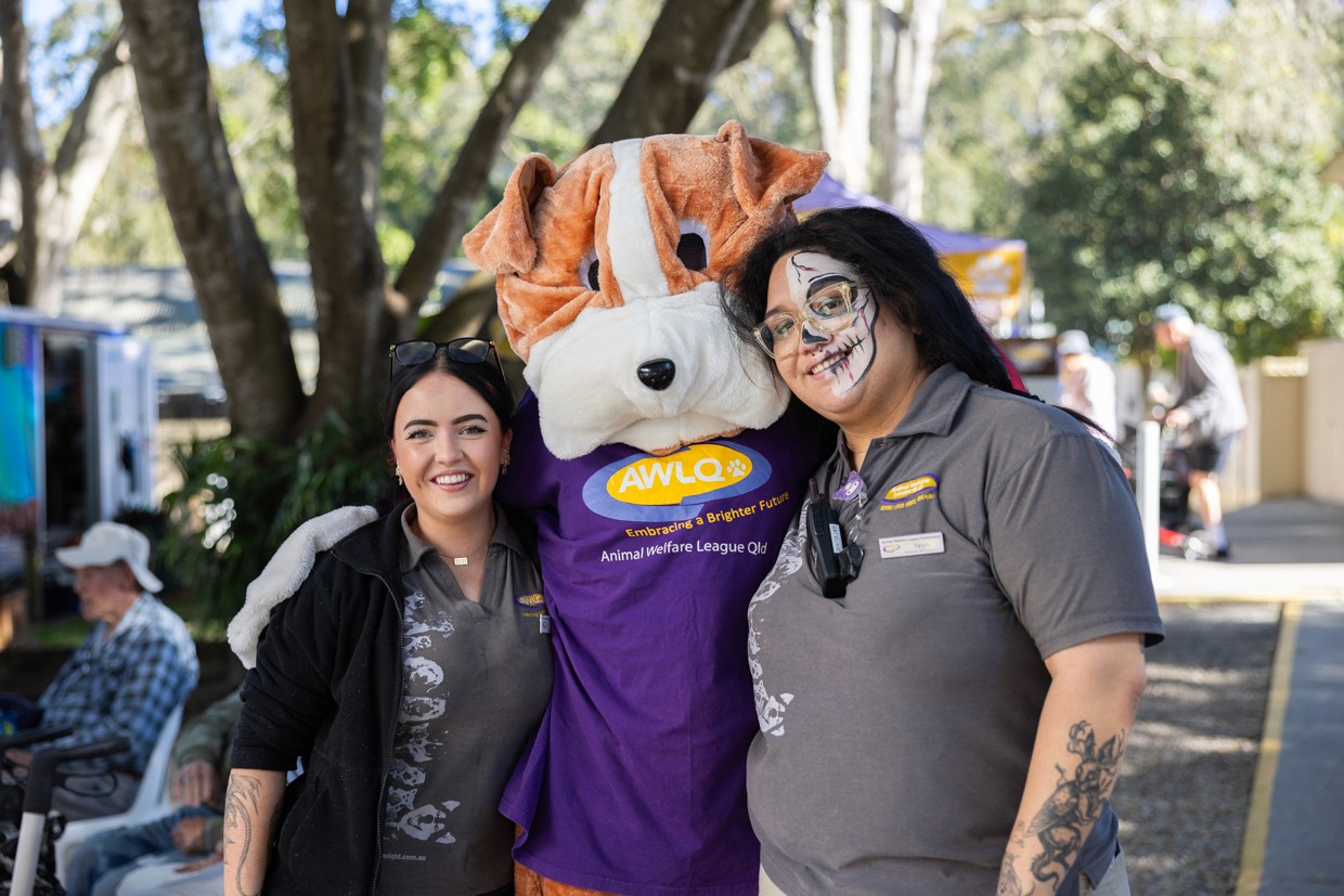 Two young women posing with dog mascot