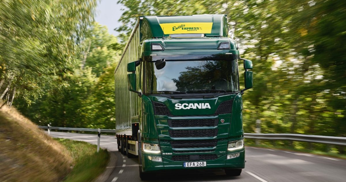 Heavy-duty electric truck driving in a green environment, representing the shift towards cleaner technologies in the trucking industry.