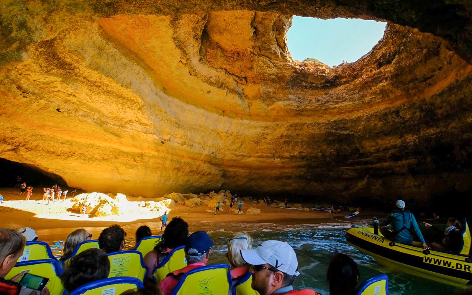 Dolphin watching tour boat entering a sea cave with tourists in Algarve, Portugal.
