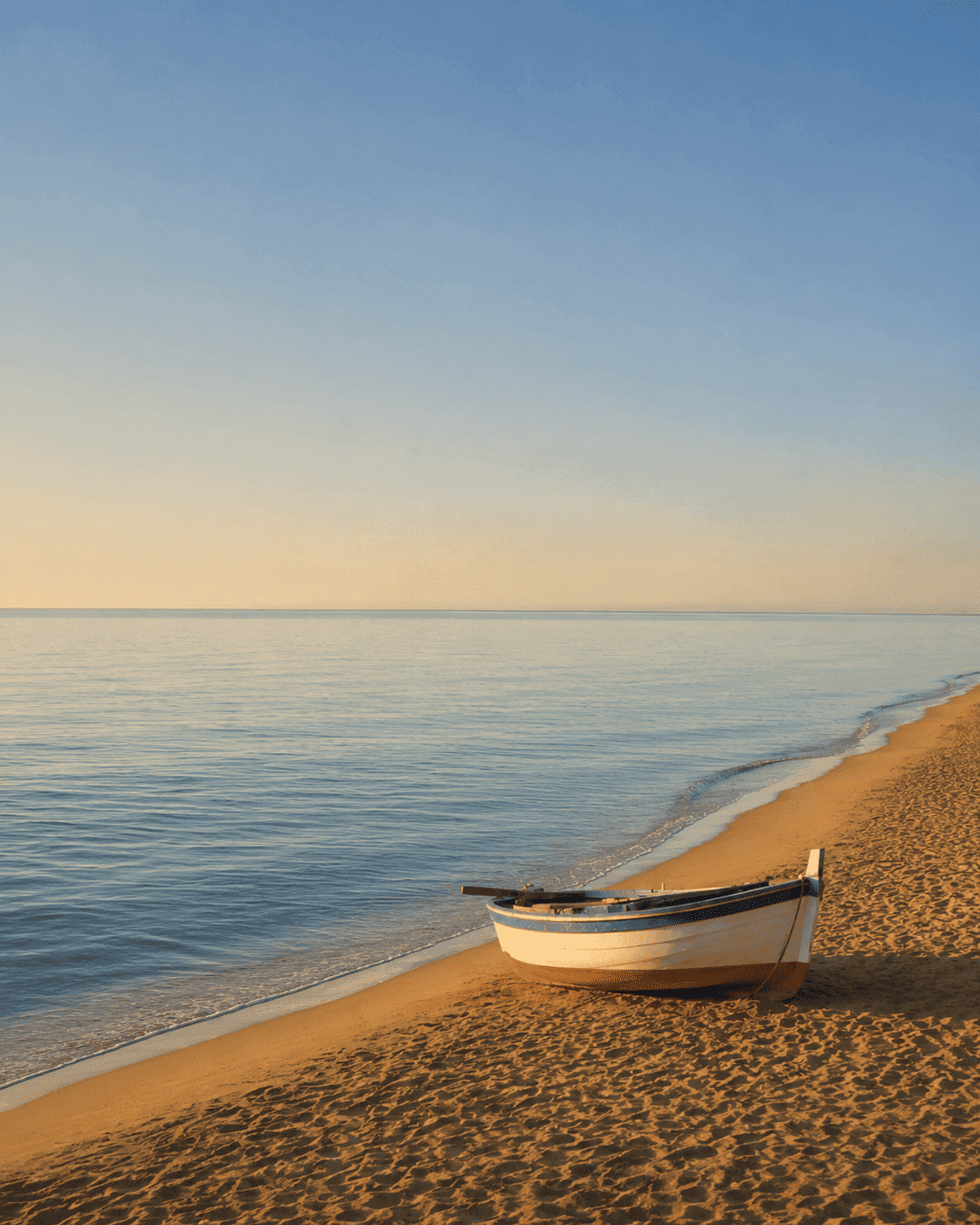 Serene Mediterranean beach scene with a small boat on the shore, representing calm coastal living and prime residential environments near Barcelona.