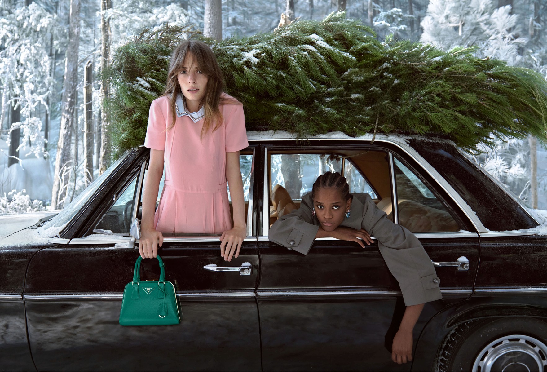 Actors Maya Hawke and Letitia Wright pictured looking out of a car in a winter landscape for the Prada WInter 2025 campaign.