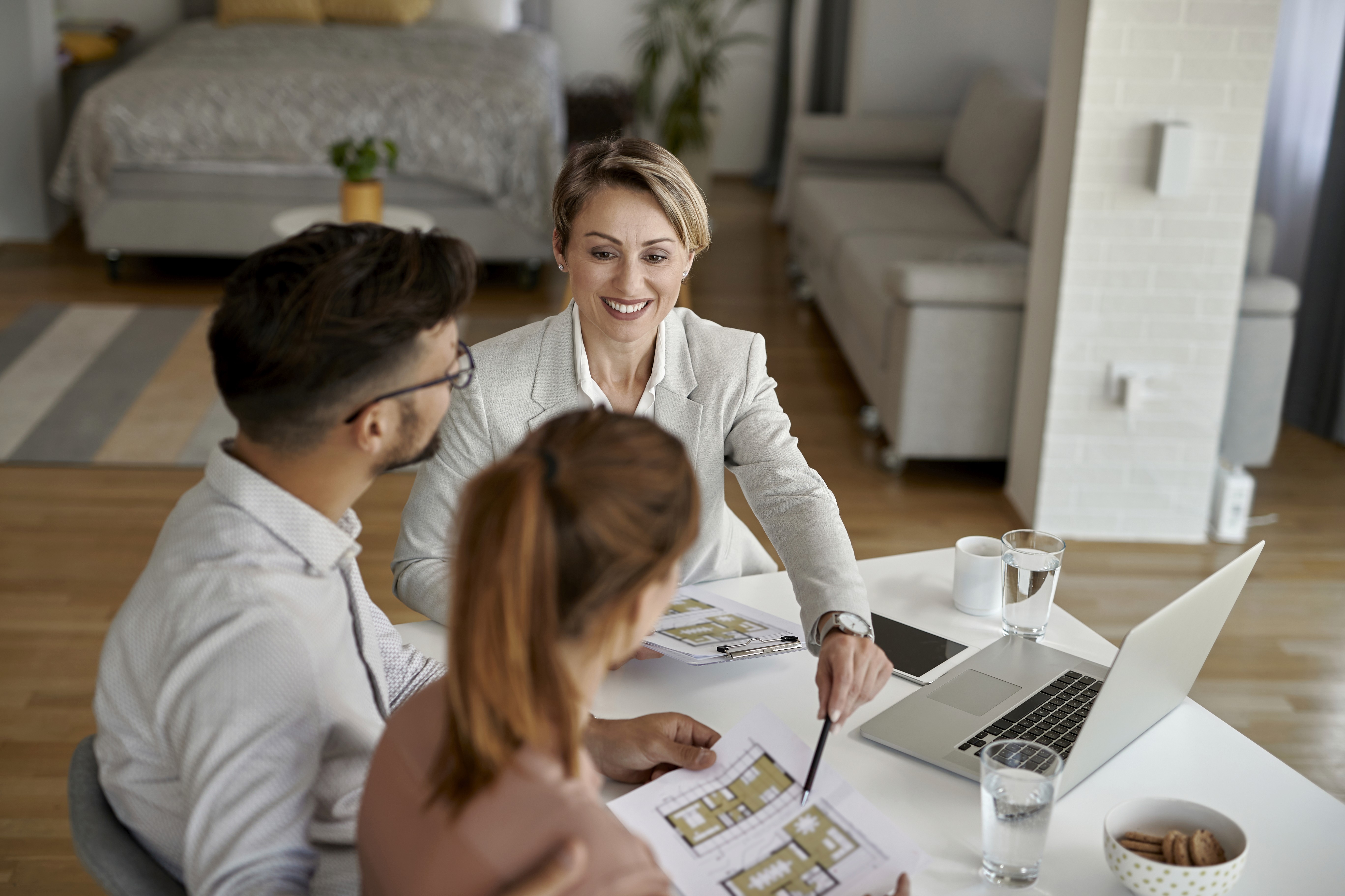 Immobilienberaterin bespricht mit einem Paar Grundriss und Finanzierung beim geplanten Hauskauf