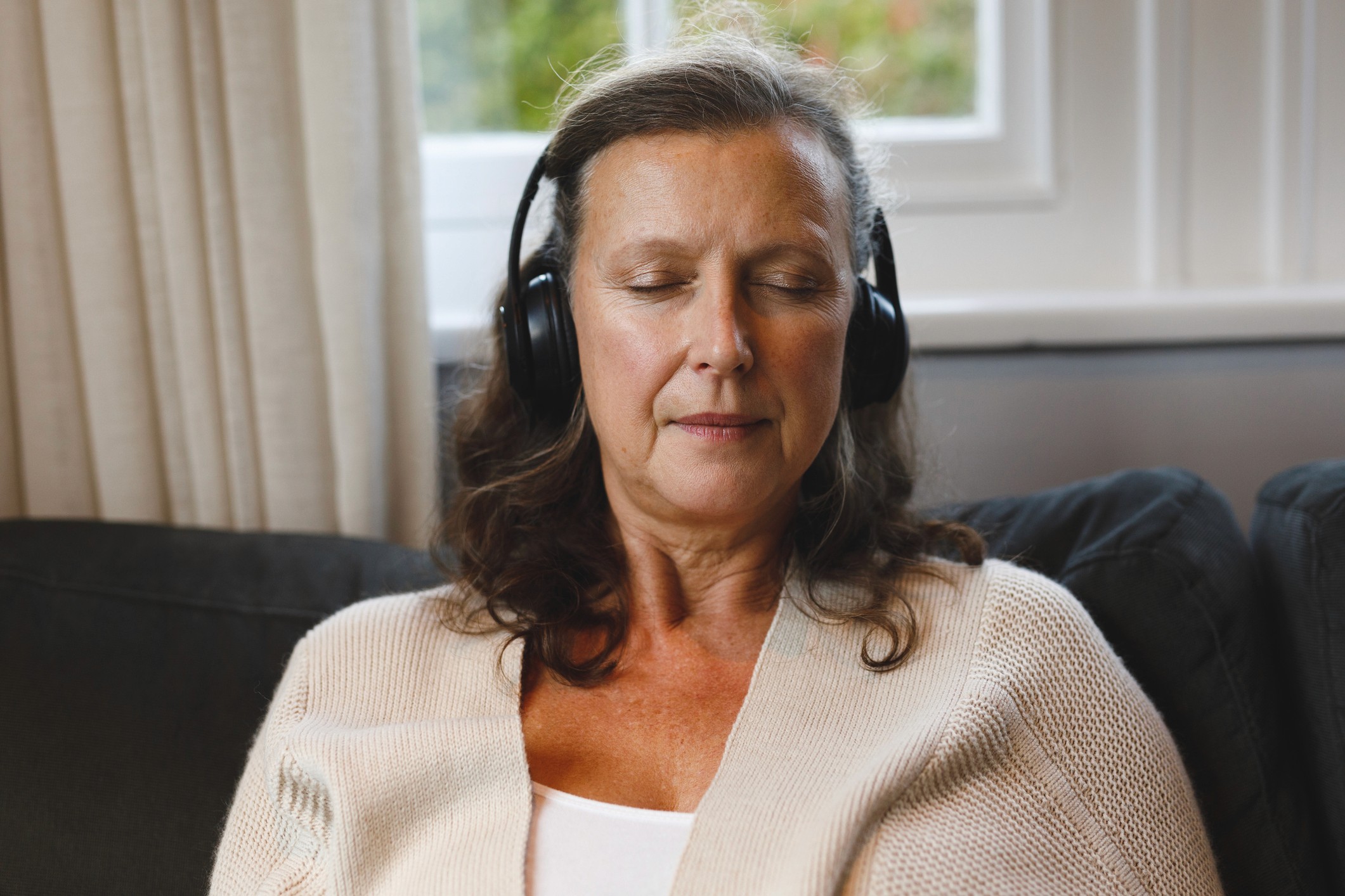 Mujer relajada con auriculares durante una sesión de terapia sonora para tratar los acúfenos o tinnitus
