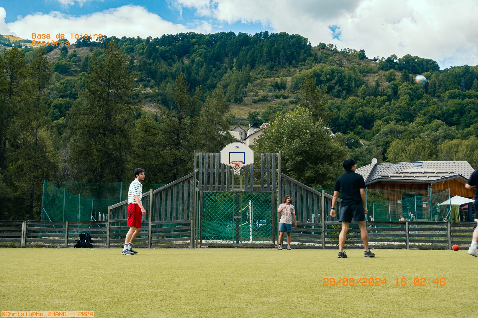 Partie de foot en plein air à la base de loisirs d’Orcières, entourée de collines verdoyantes.