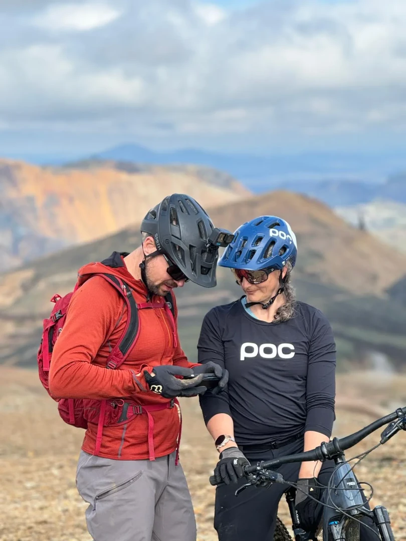 Two riders look at their phone while on a biketour in icealnd