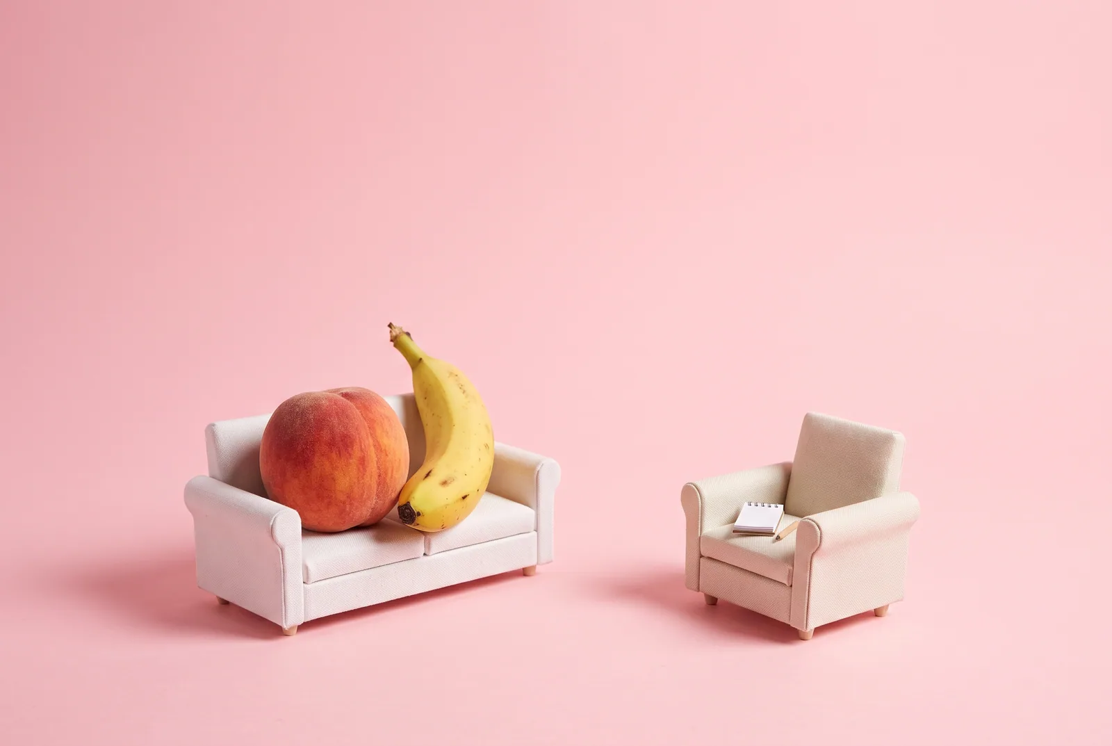 A peach and a banana on a small sofa facing an empty armchair, couples therapy when your husband looks at other women online