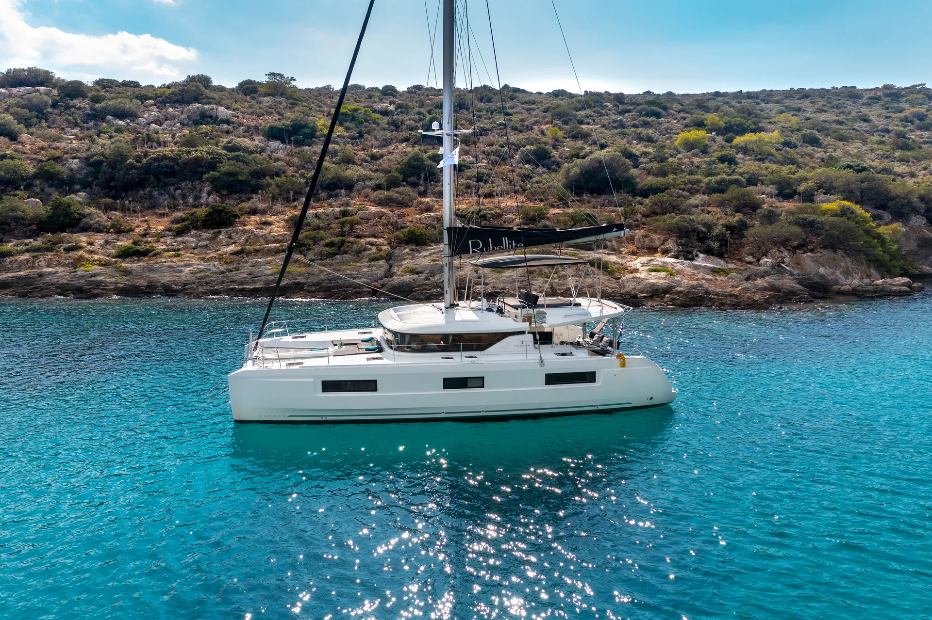 White Rock 36 speedboat with captain at helm cruising calm blue waters near Paros coastline with hills in background.