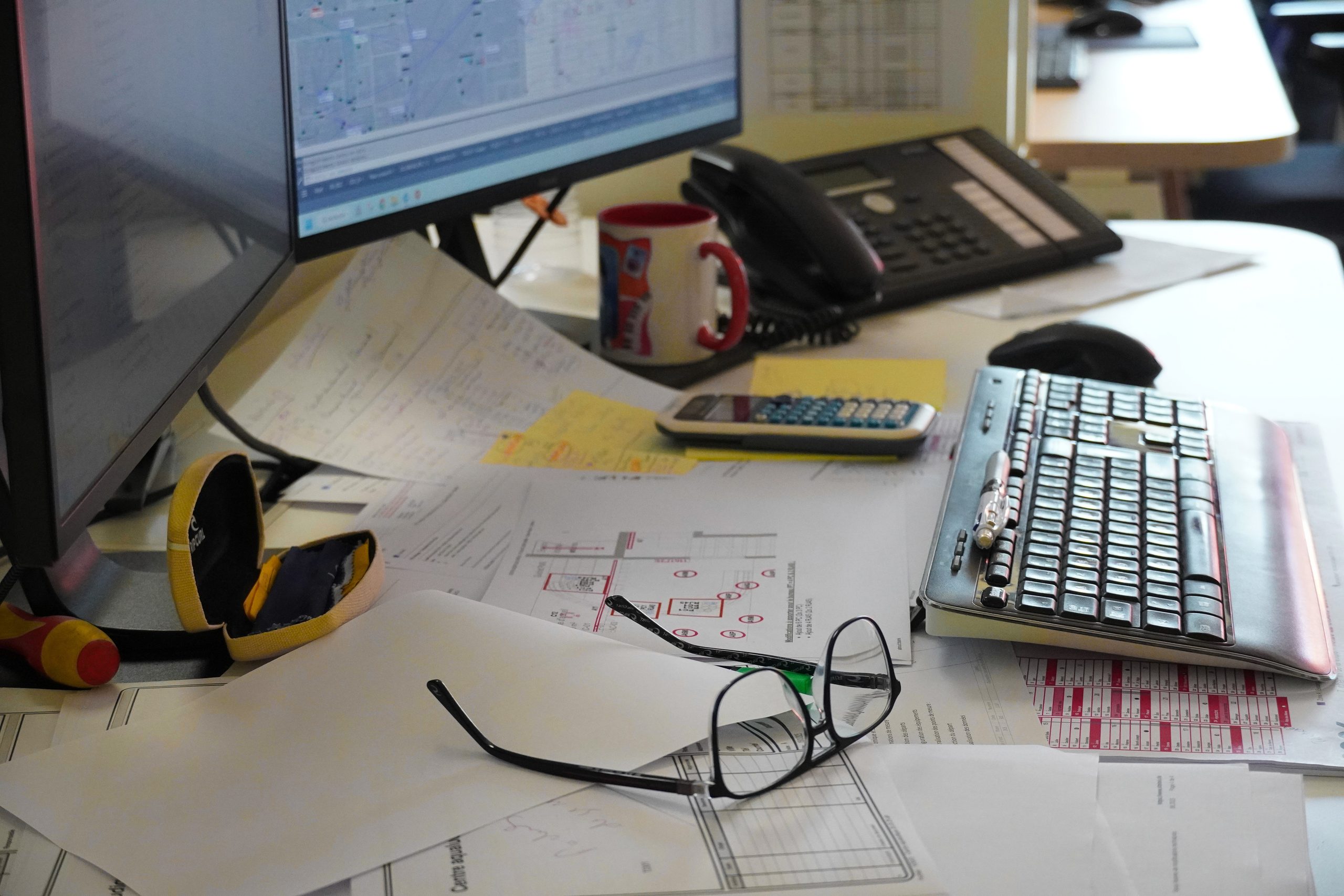 Plans électriques et outils de chiffrage sur le bureau d'un chargé d'affaires