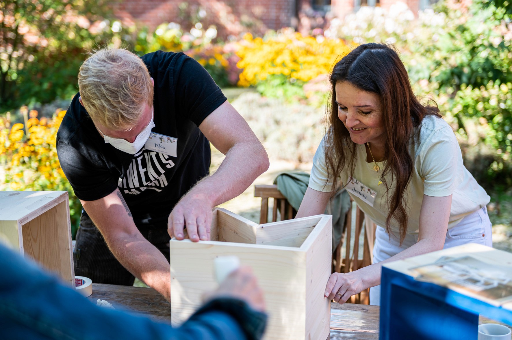 Beim Workshop mit toom arbeiten Teilnehmende gemeinsam an einem Holzprojekt im Grünen.