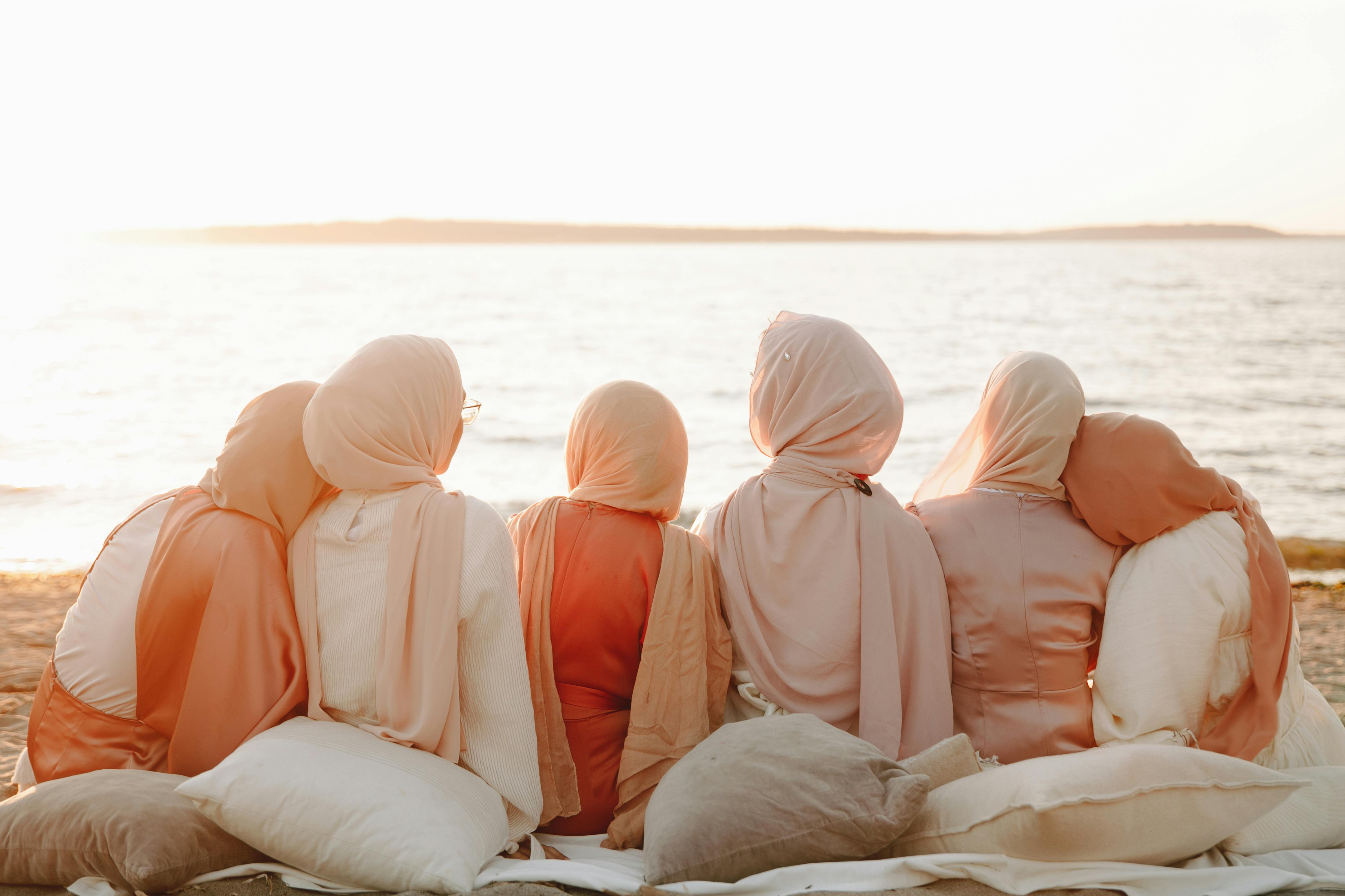 Hijabi Muslim ladies sitting together on the beach