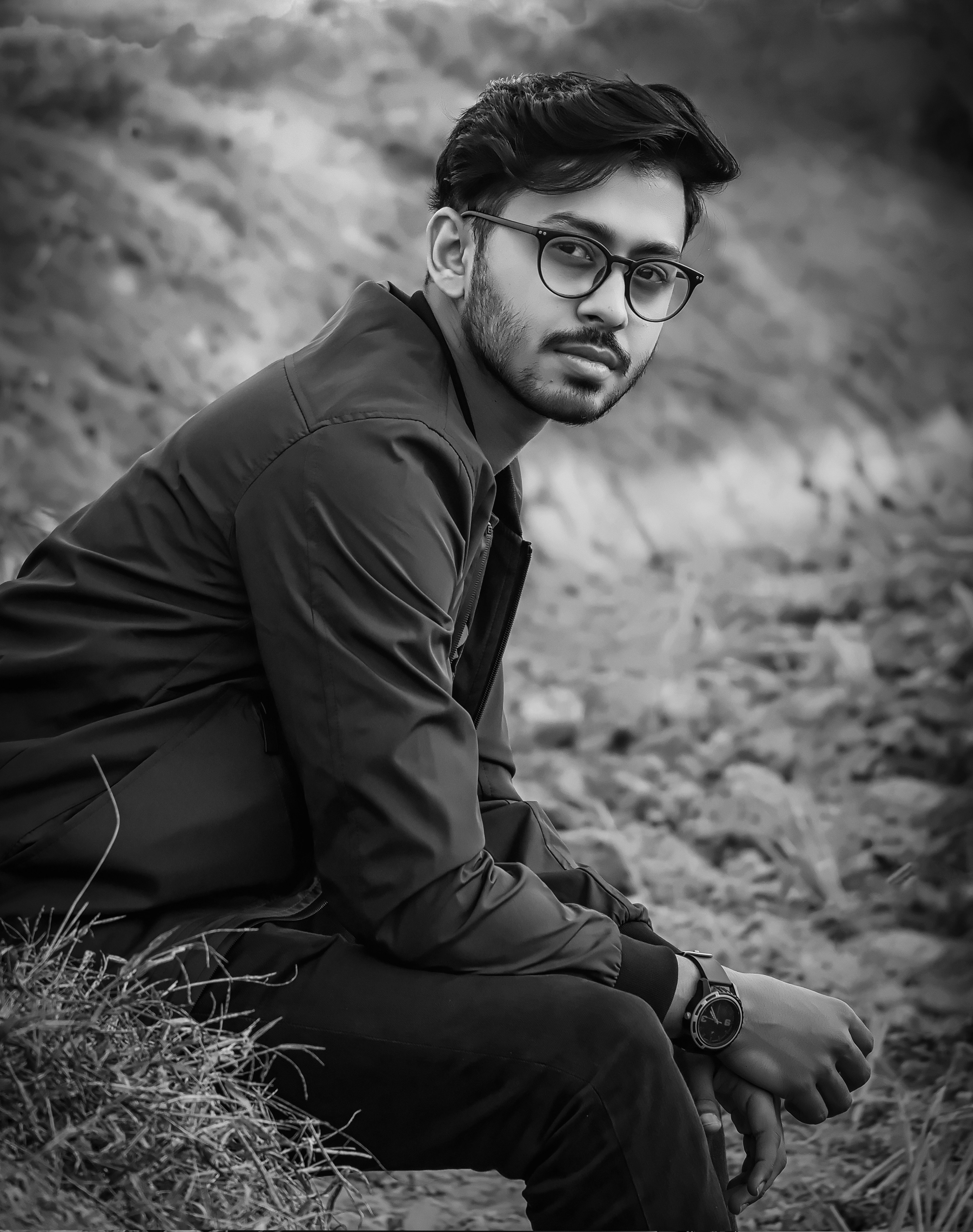 man in black jacket and black pants wearing black sunglasses sitting on grass