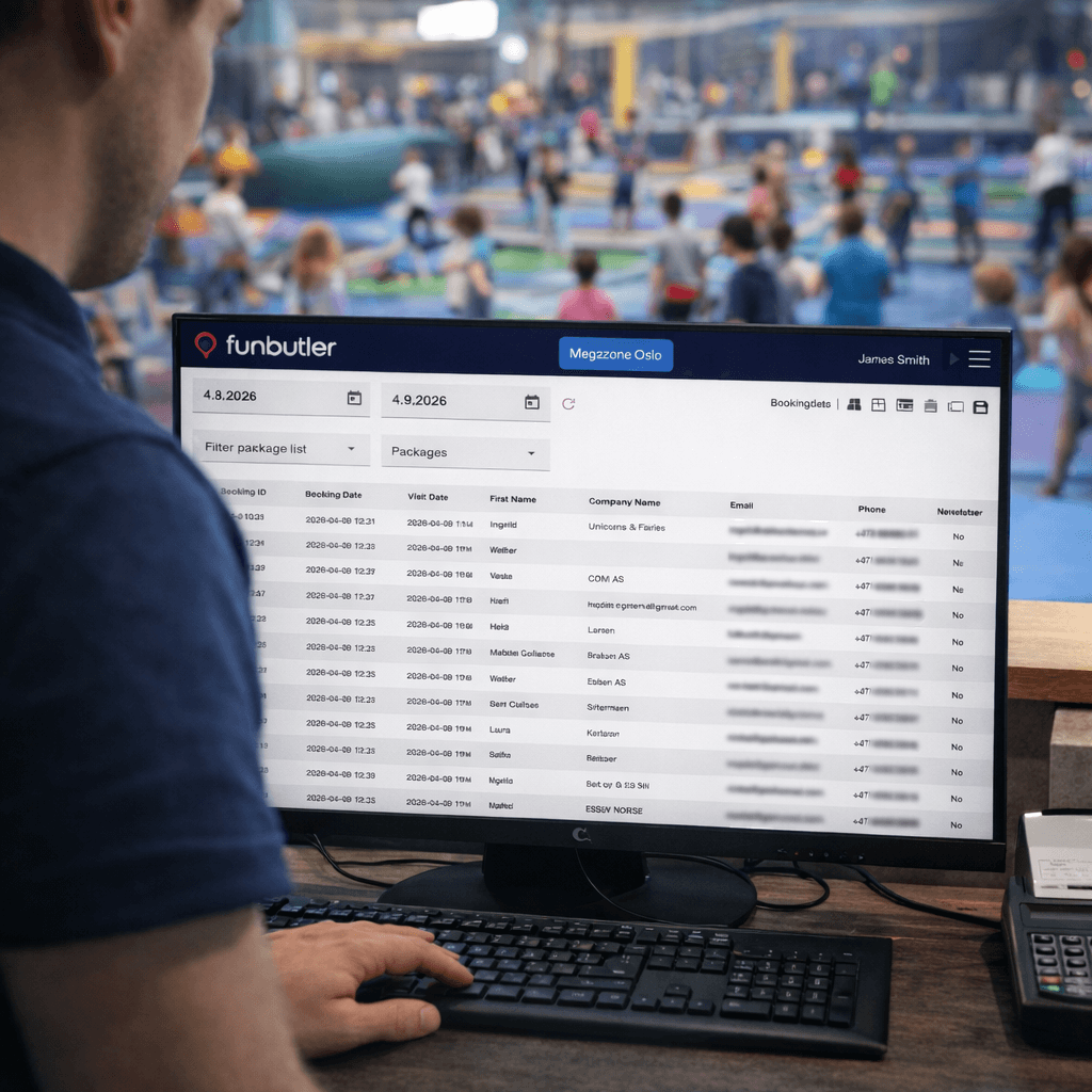 A young person with curly hair smiles at the camera while sitting in front of a laptop against a dark background.