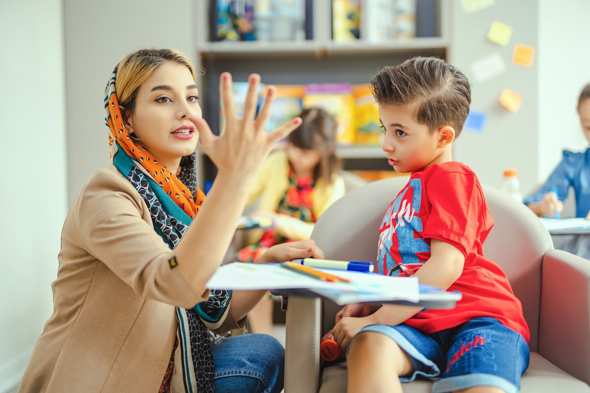 Illustrative stock photograph of an educator supporting a student in a welcoming classroom; not TCFMH staff or clients.