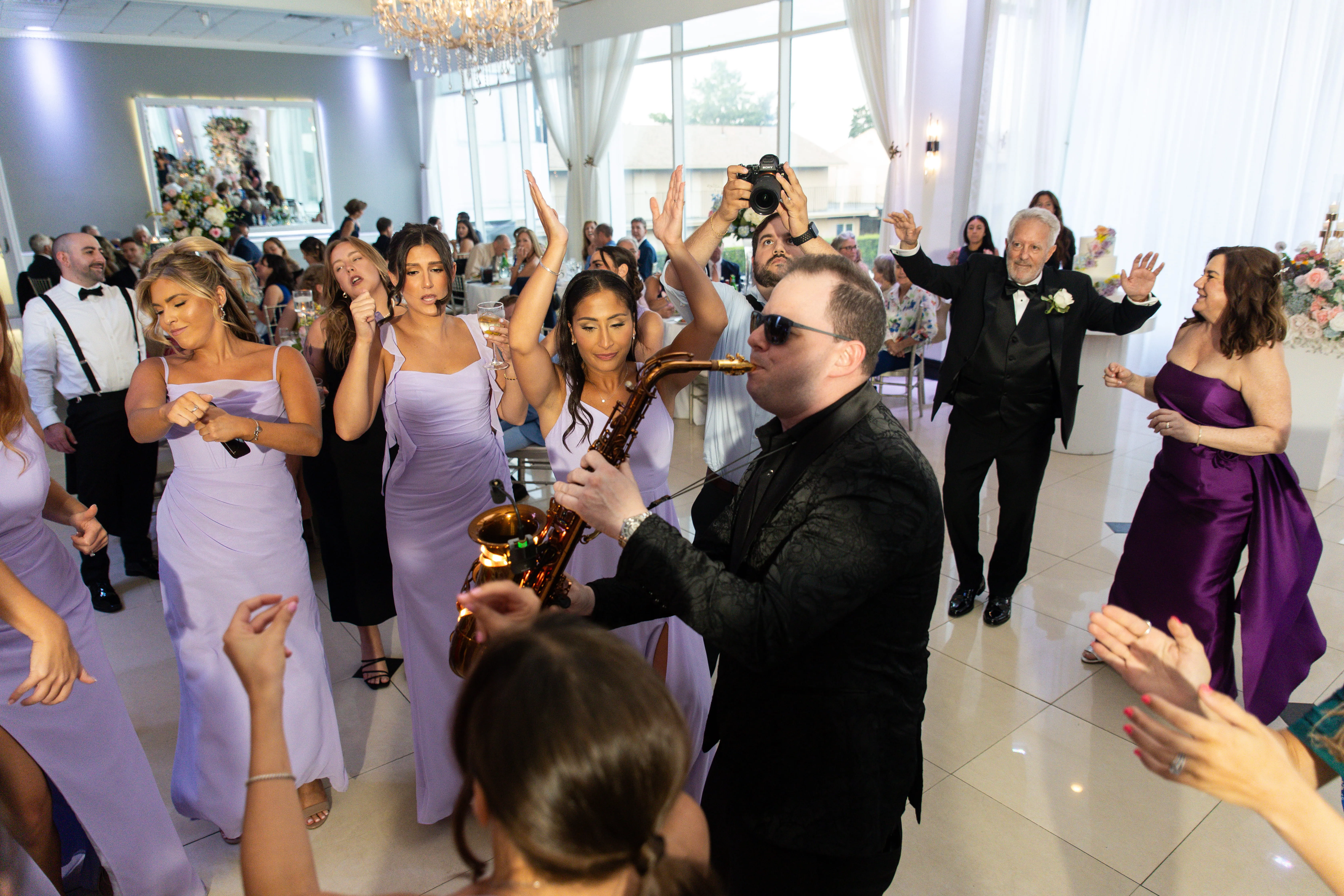 Wedding DJ performing with live saxophone musician on dance floor