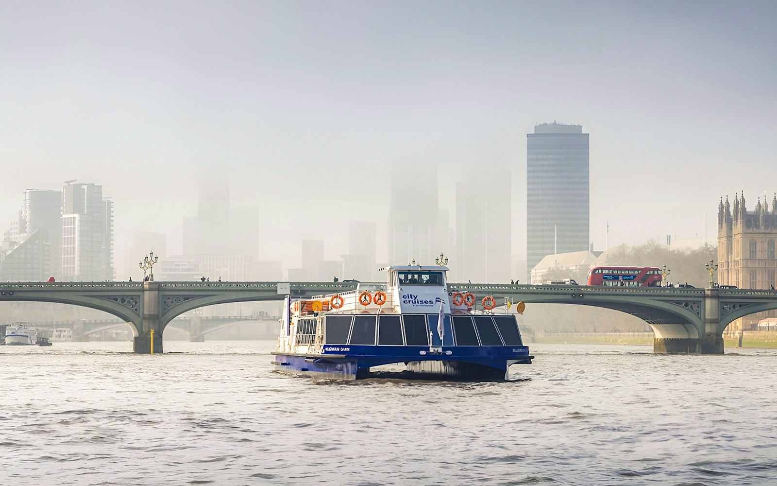 Thames-elvbåttur med Londons skyline og bro i bakgrunnen.