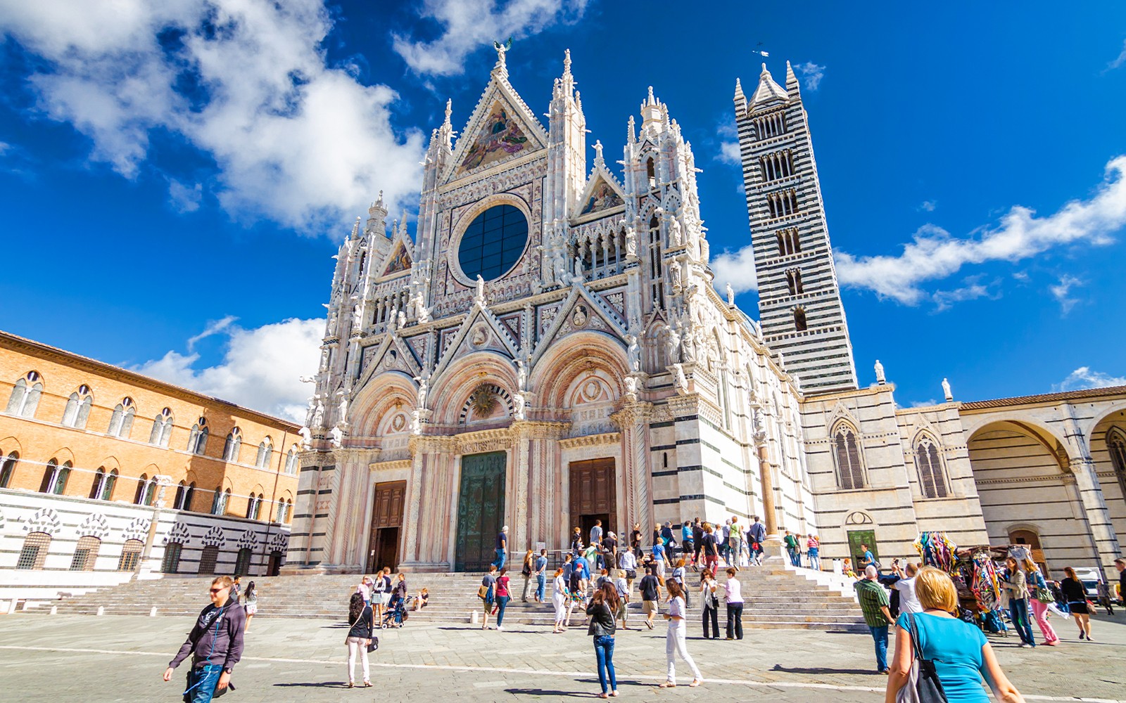 Siena Cathedral facade with visitors in Piazza del Duomo, Italy.