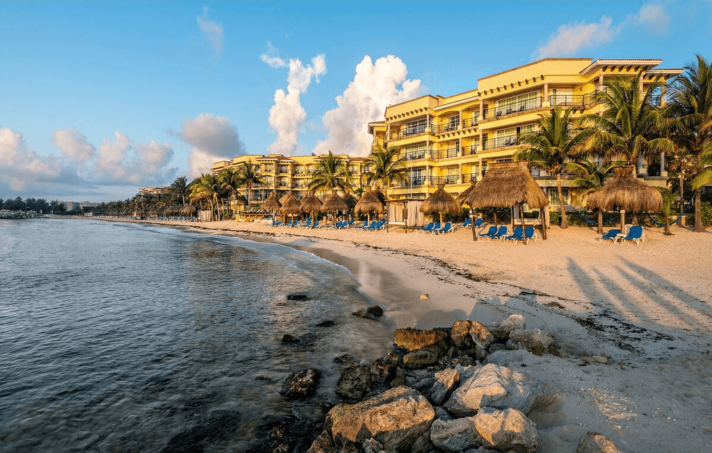 Couple standing on a balcony with binoculars in hand looking out over the ocean