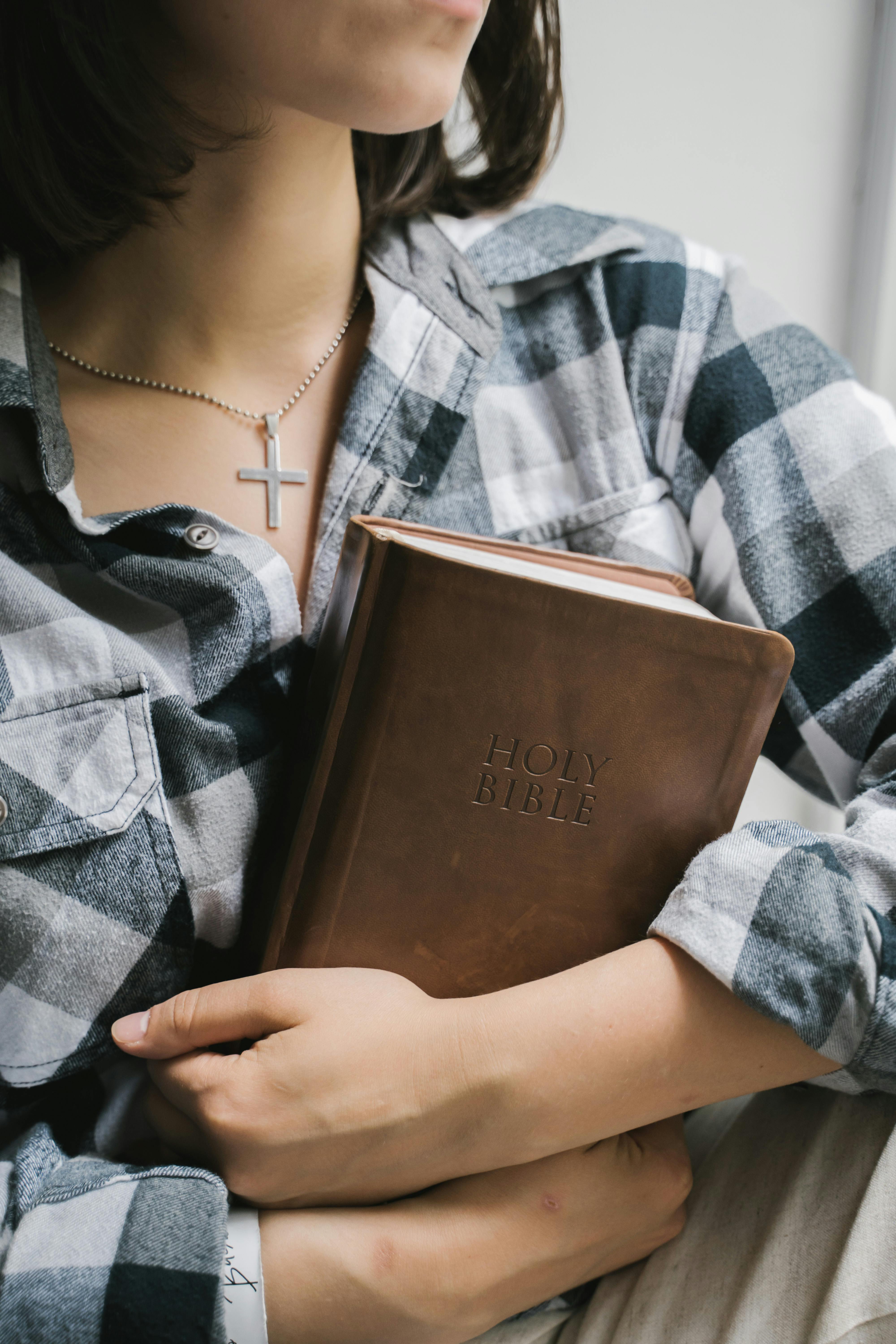 Conversion Truth for Families - Young woman in plaid shirt holding a brown leather-bound Holy Bible