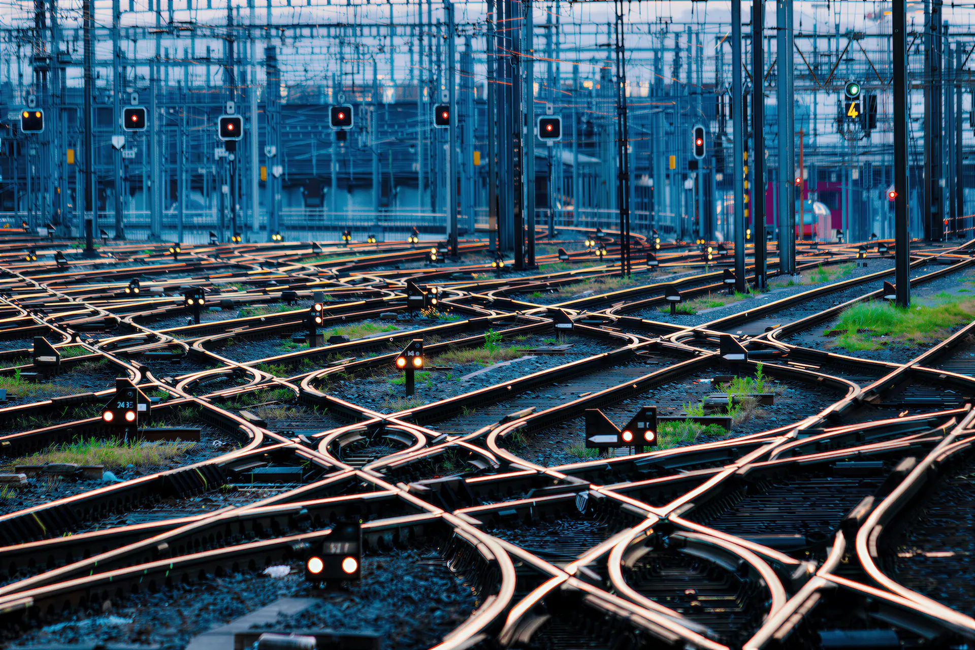 Railway switching yard at dusk with intersecting tracks and signal lights guiding unified routes