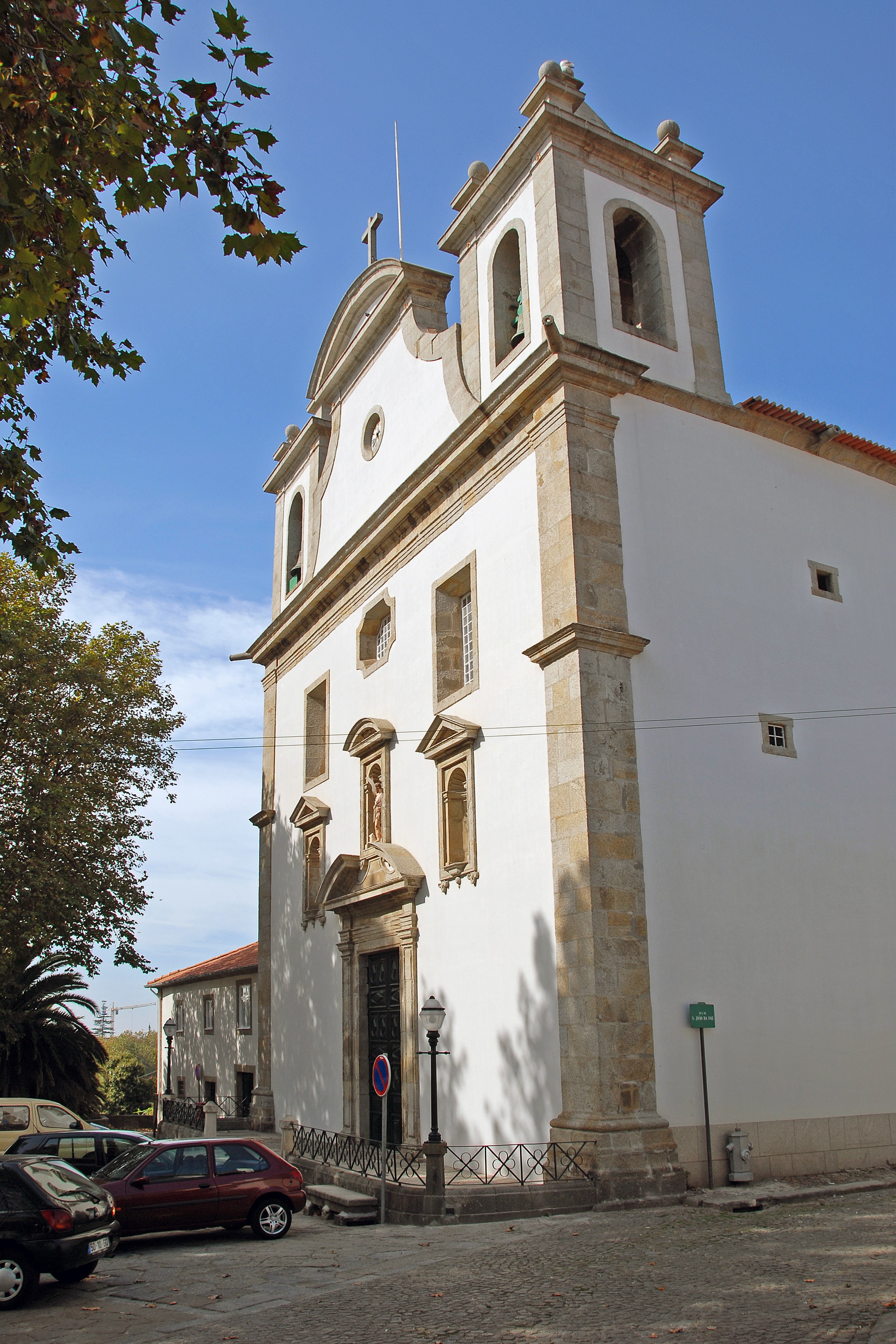 A serene outdoor wedding setup with white chairs arranged on green grass under a canopy of trees.