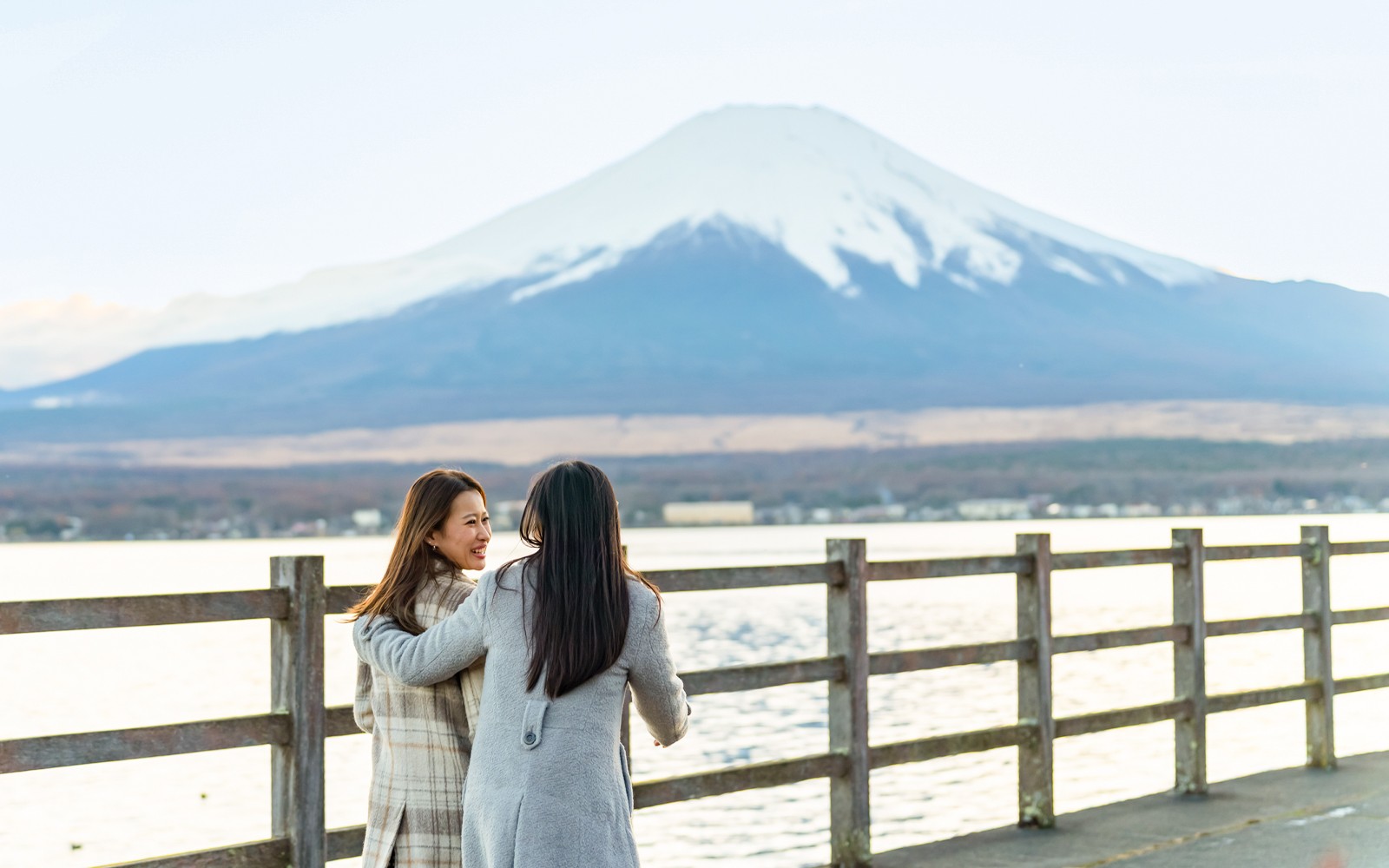 Dalawang babae ang naglalakad patungo sa Bundok Fuji sa Japan, na may makikitang ikonikong taluktok sa background.