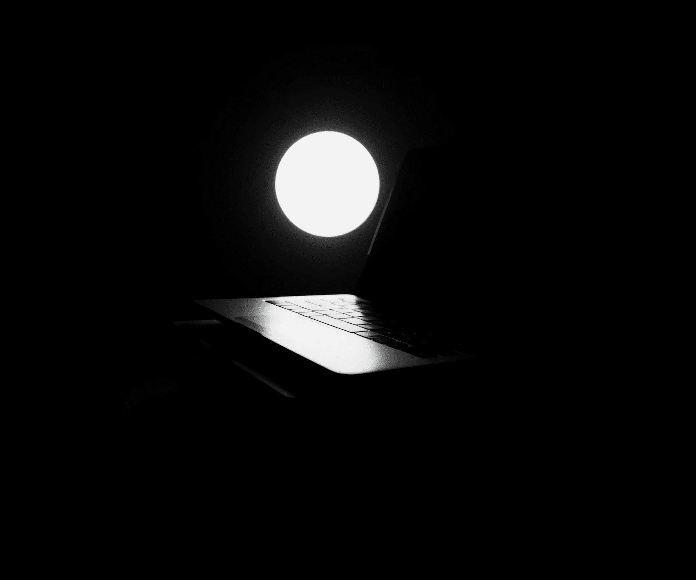 Laptop with glowing orb in darkness — symbolizing the moment of strategic insight before starting a website redesign project