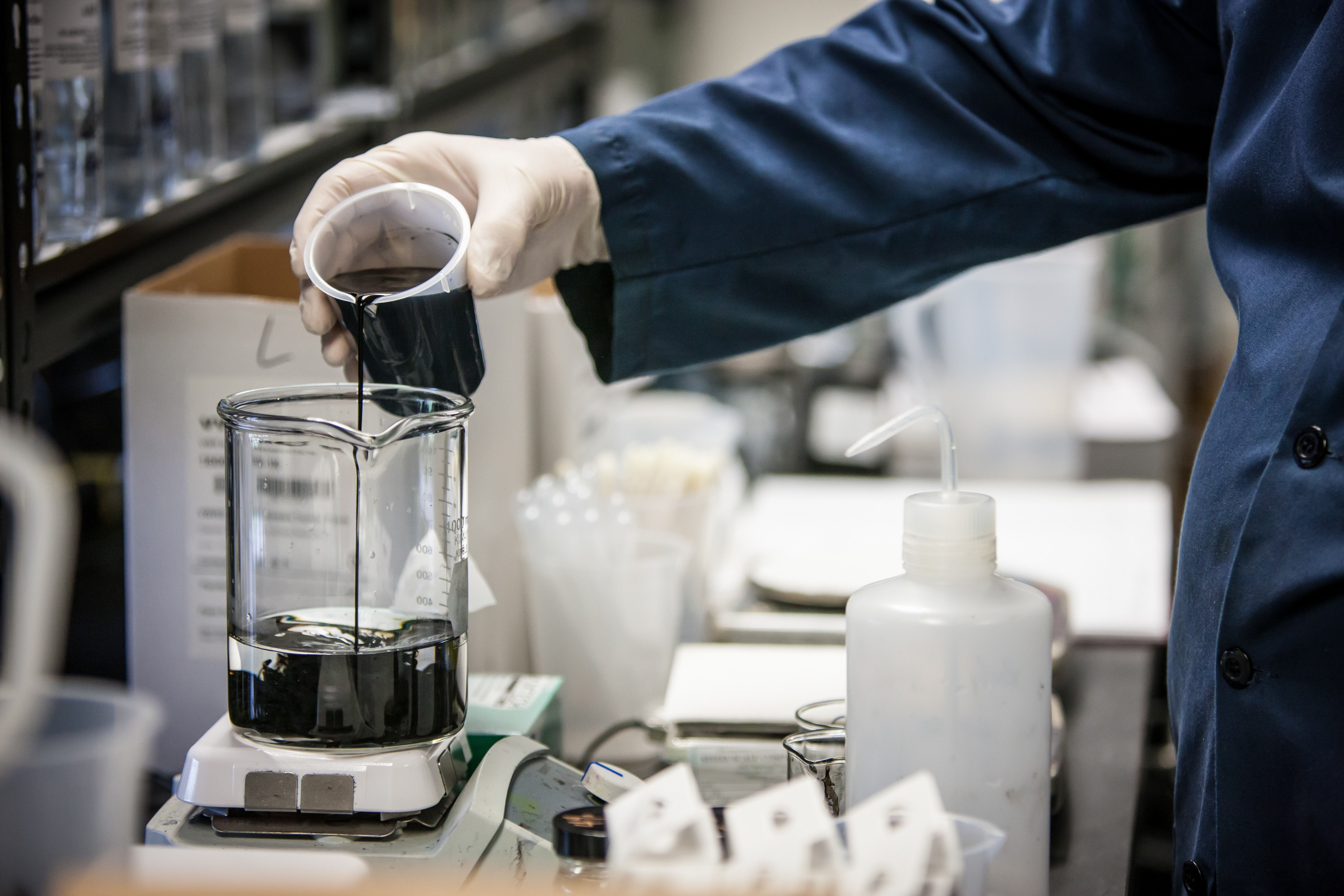 Scientist in a lab, pouring liquid into a beaker.