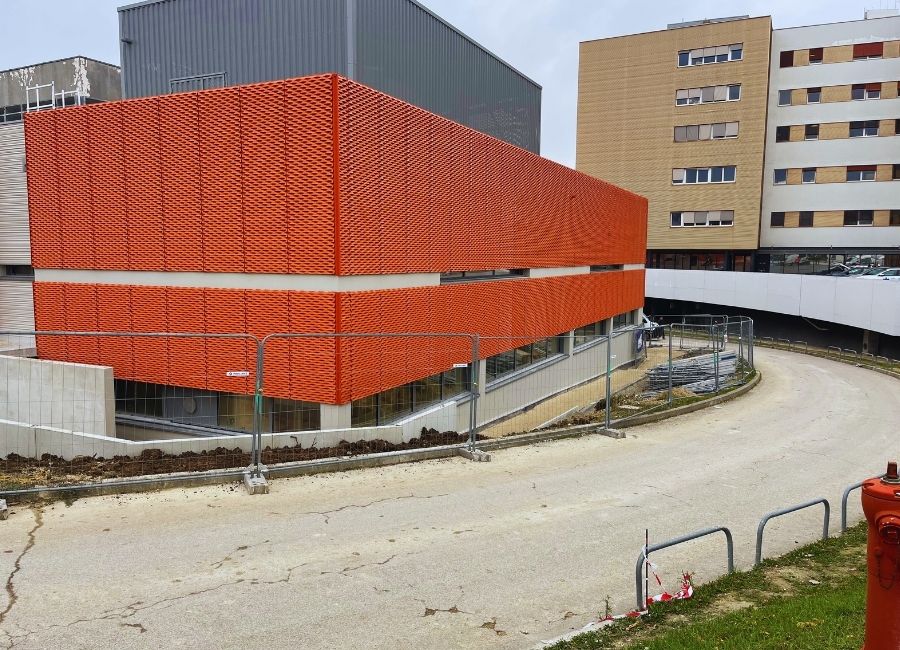 Bâtiment en construction avec couverture en tôle rouge, situé en zone urbaine.