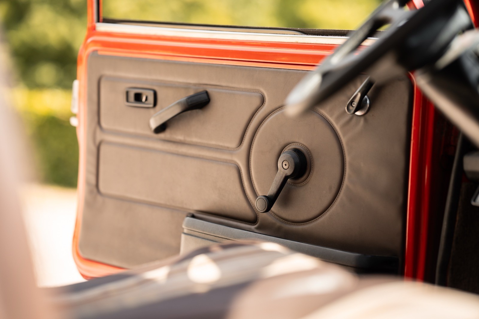 Close-up of a vintage car's dashboard with controls for the radio and air conditioning. Sunlight filters through.